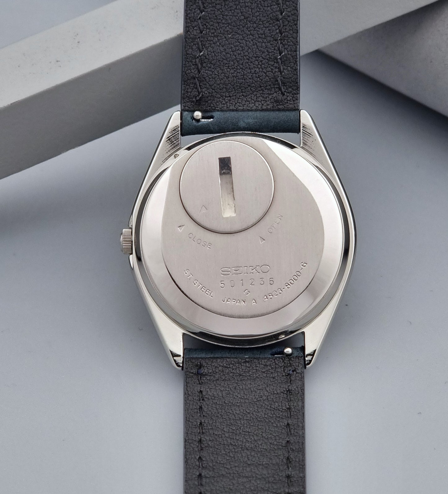 Vintage Seiko King Quartz 4823-8000-G with a blue leather strap on a dark background case back view
