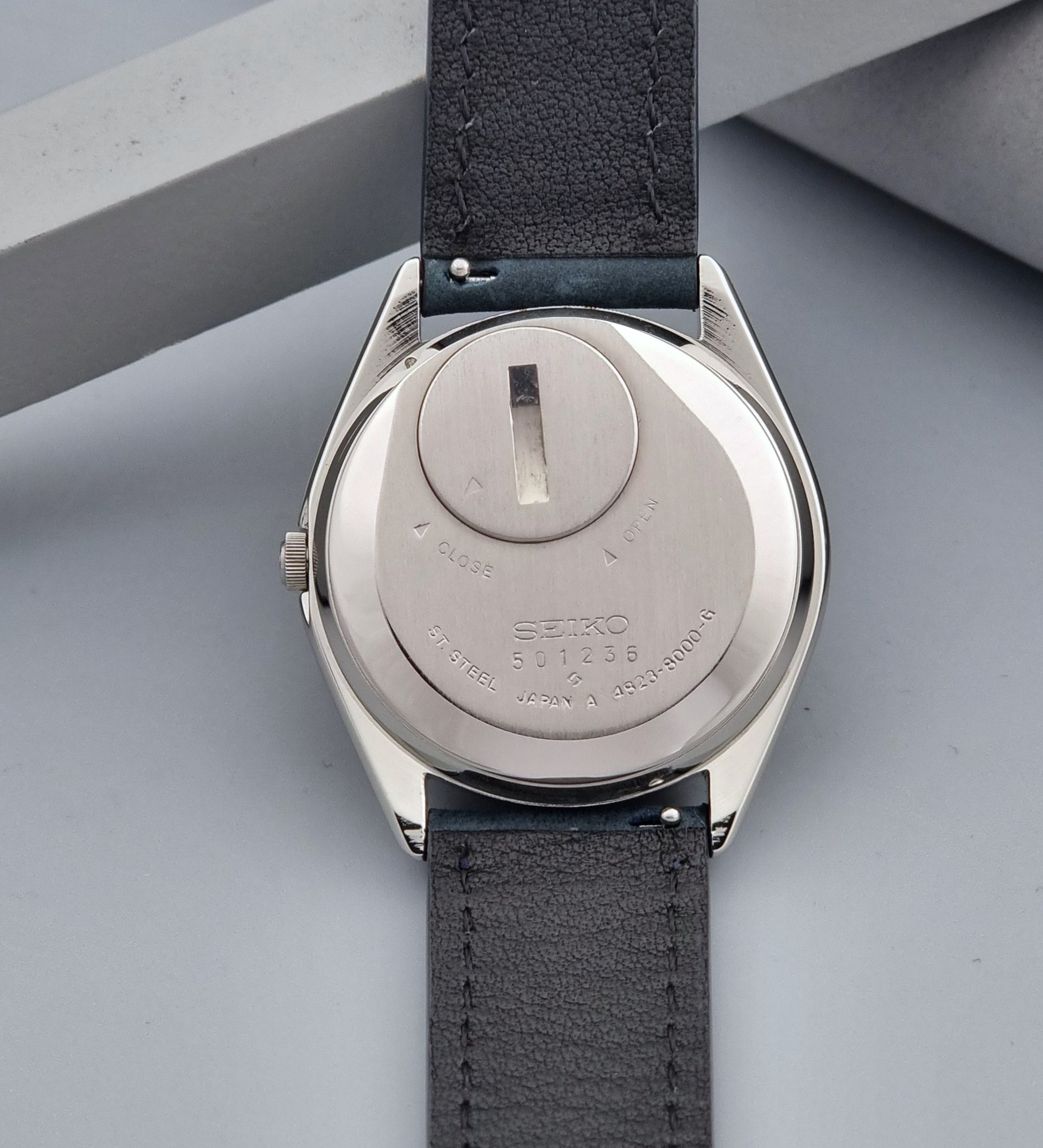Vintage Seiko King Quartz 4823-8000-G with a blue leather strap on a dark background case back view