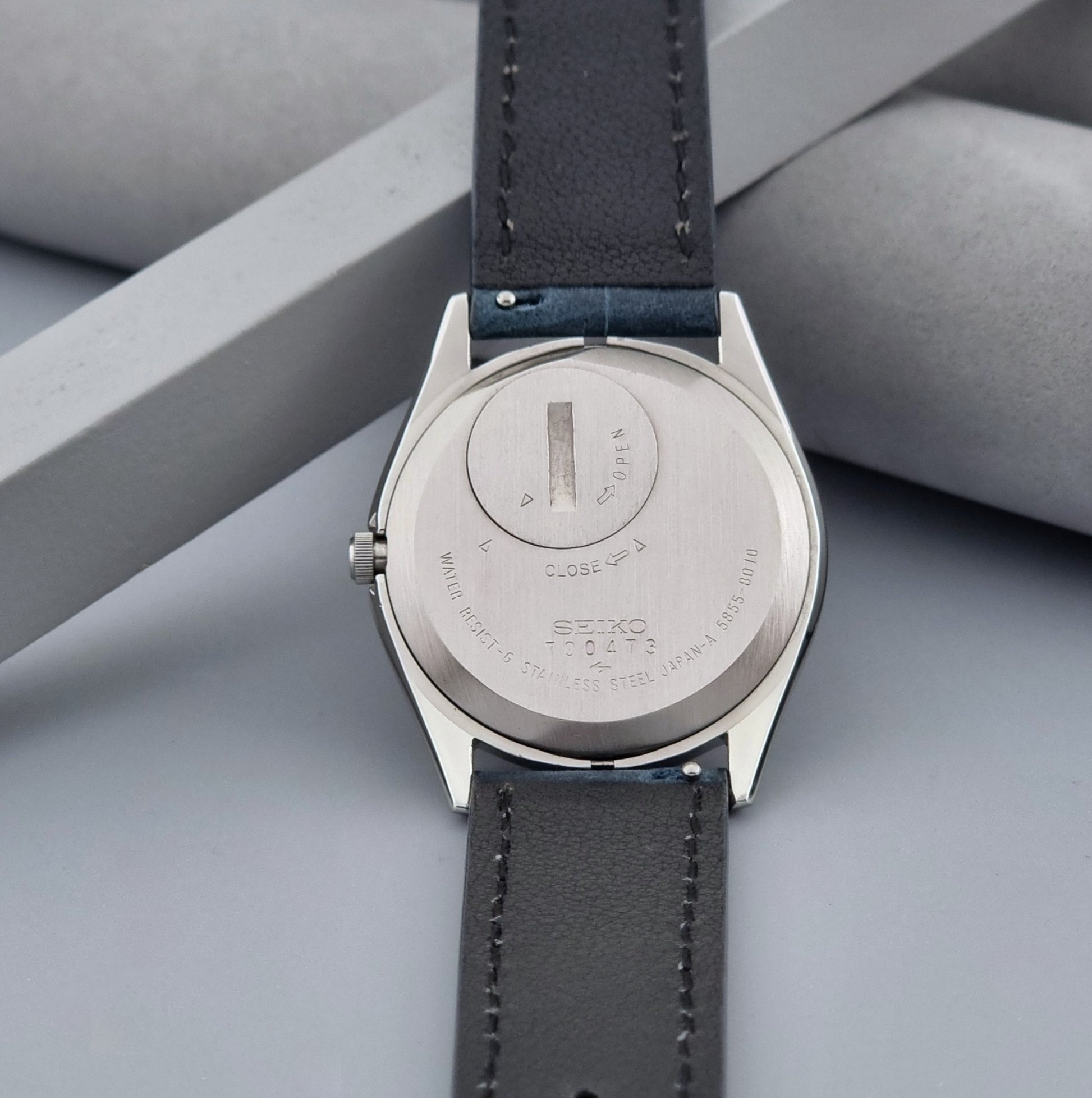 Vintage Seiko King Quartz watch 5855-8010 with blue leather strap on a gray background case back view