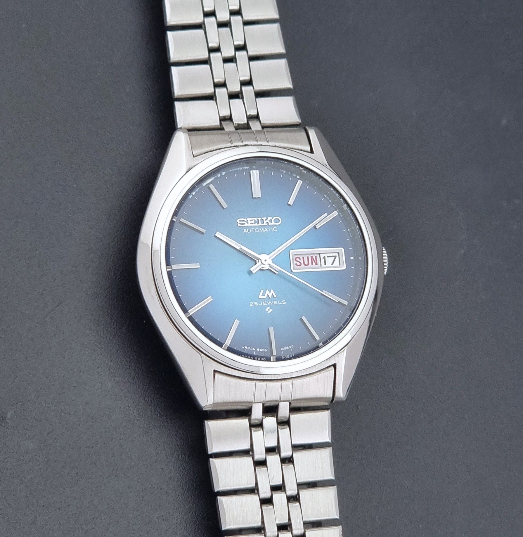 Vintage Seiko LordMatic 5606-8030 Wristwatch with blue dial on dark background front view