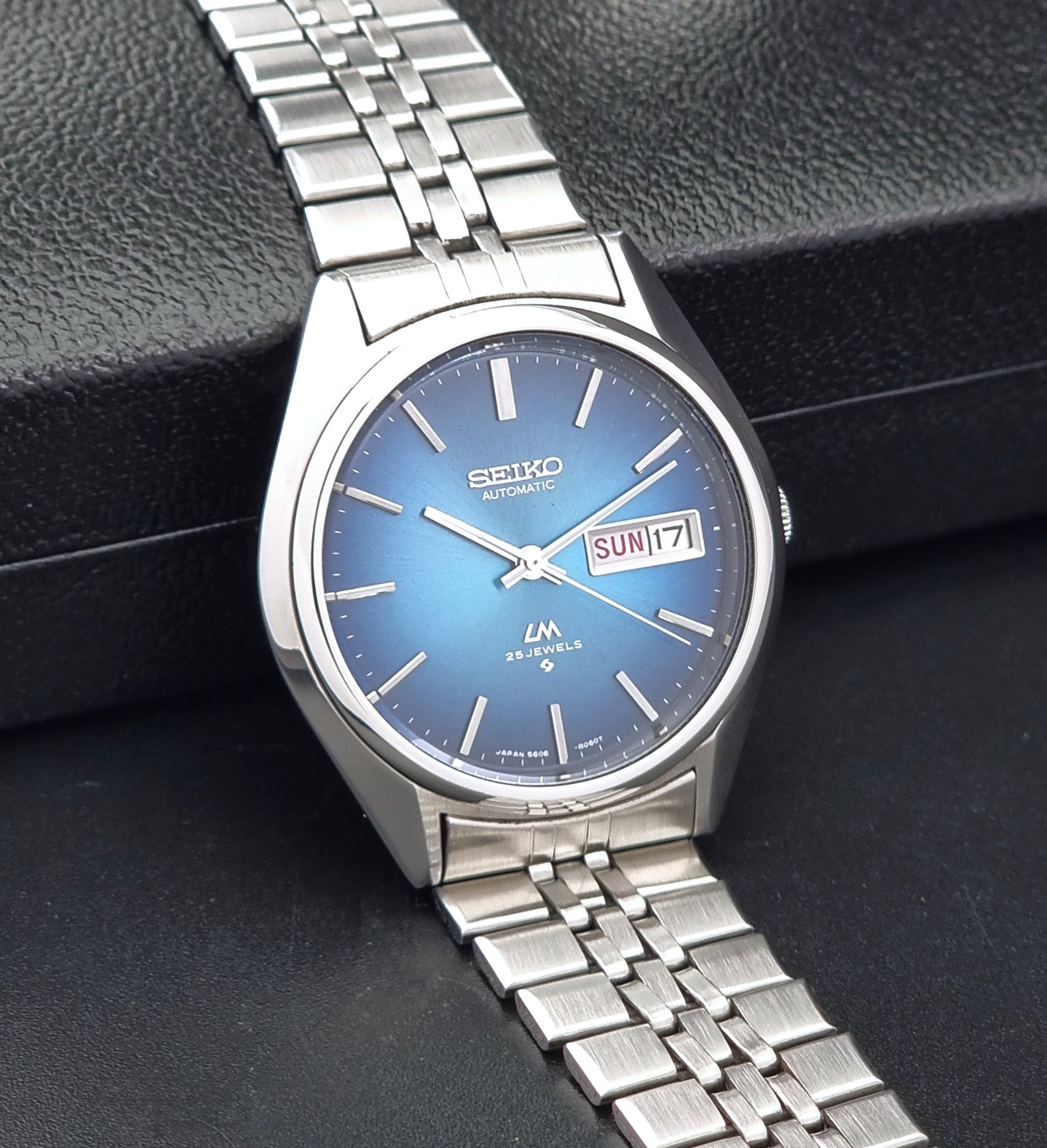 Vintage Seiko LordMatic 5606-8030 Wristwatch with blue dial on dark background sid eview