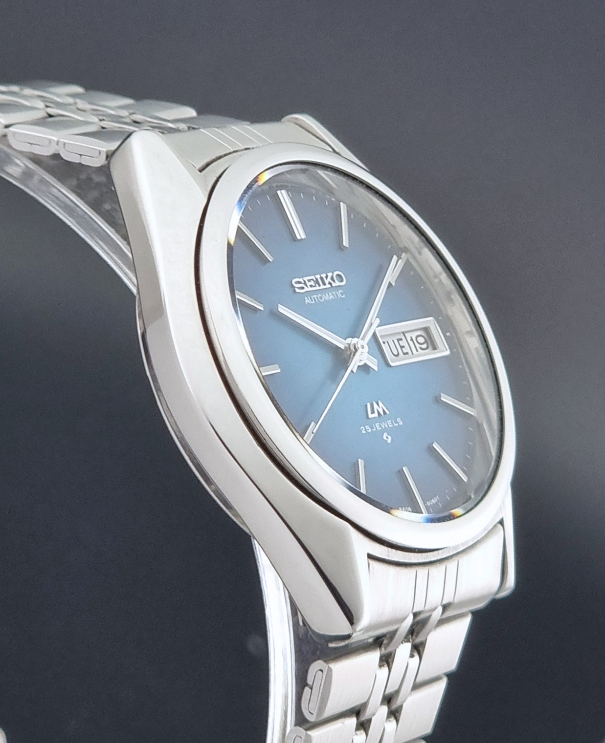 Vintage Seiko LordMatic 5606-8030 Wristwatch with blue dial on dark background side profile view