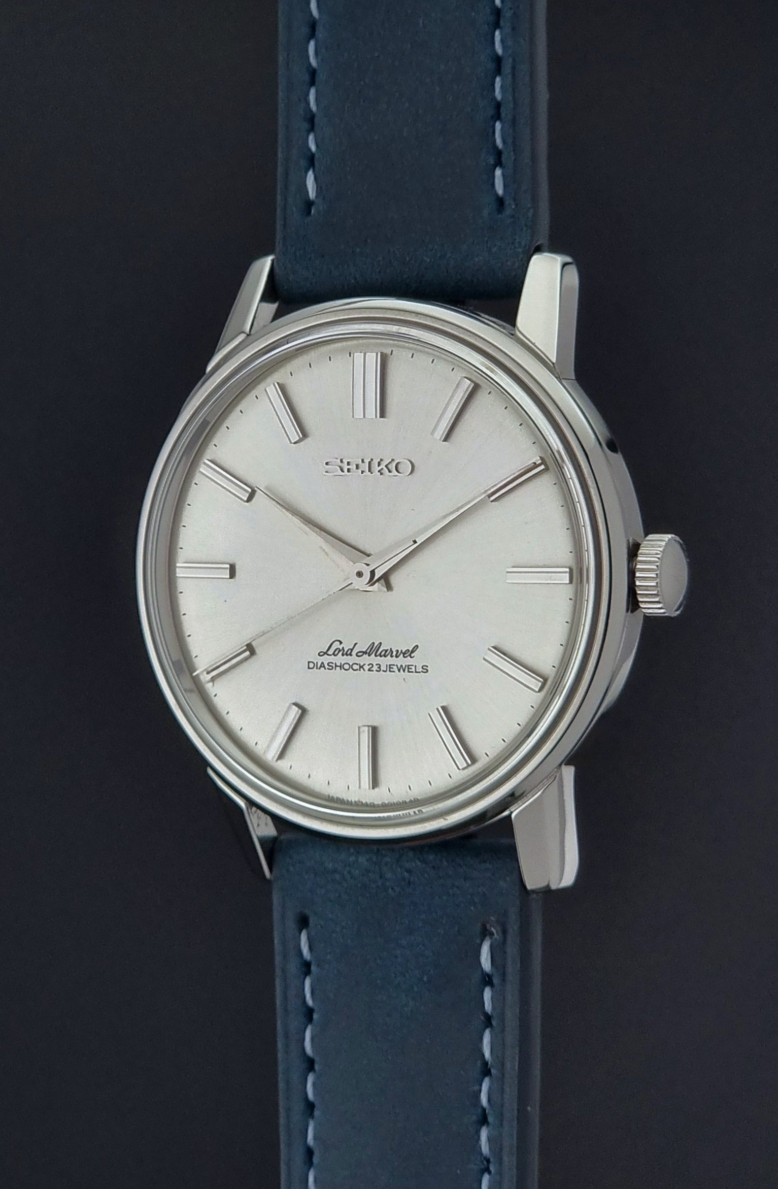 Vintage Seiko Lord Marvel wristwatch with blue leather strap and silver case on a dark background