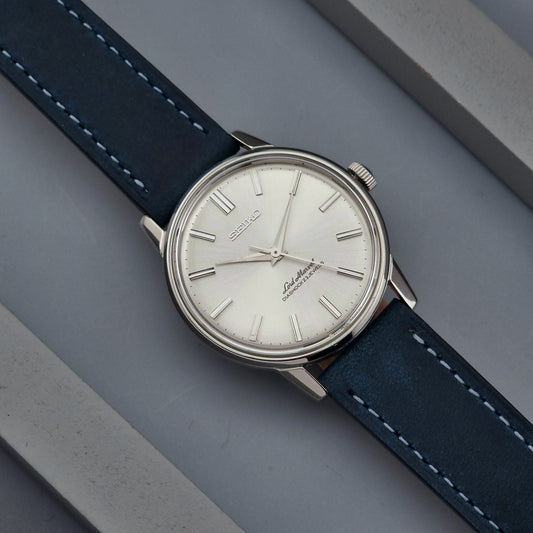 Vintage Seiko Lord Marvel wristwatch with blue strap on a gray surface