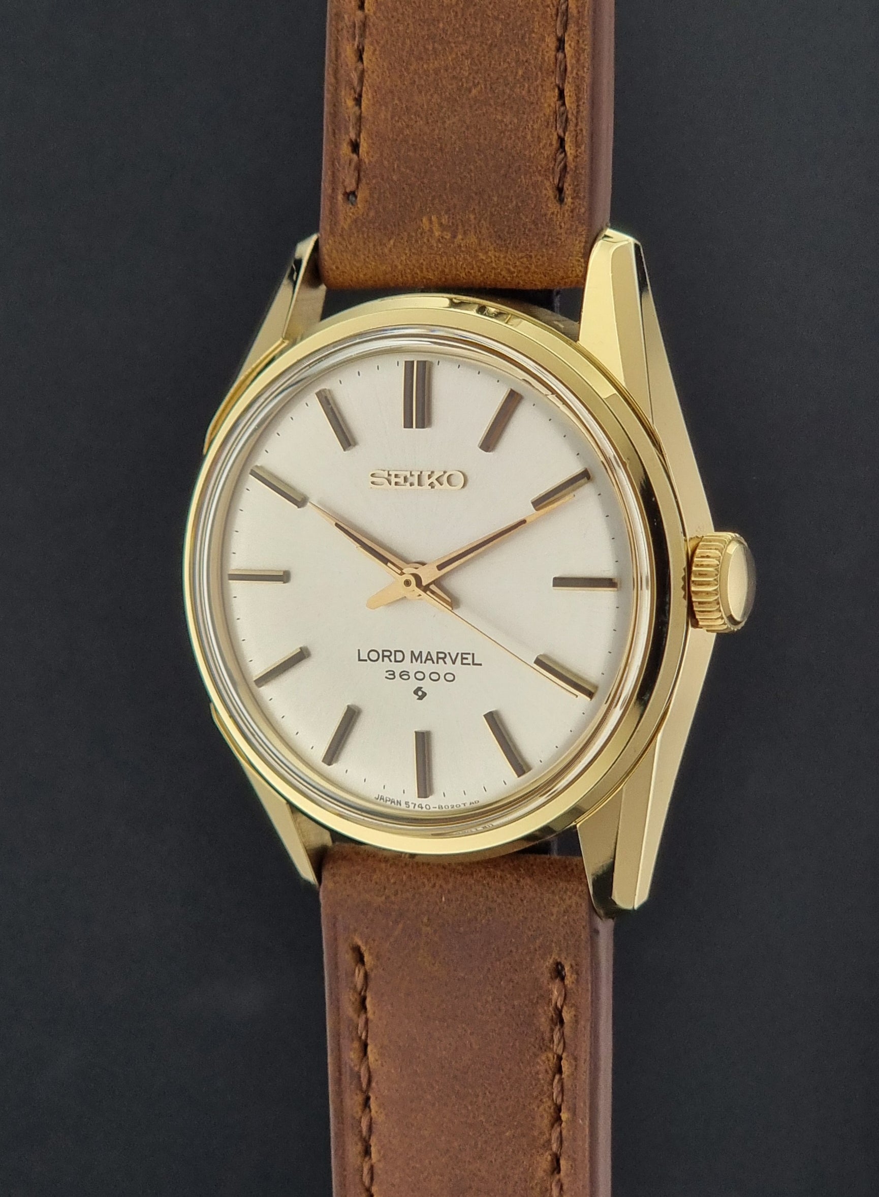 Vintage Seiko watch Lord Marvel 5740-8000 with brown leather strap and gold case on a dark background crown profile view