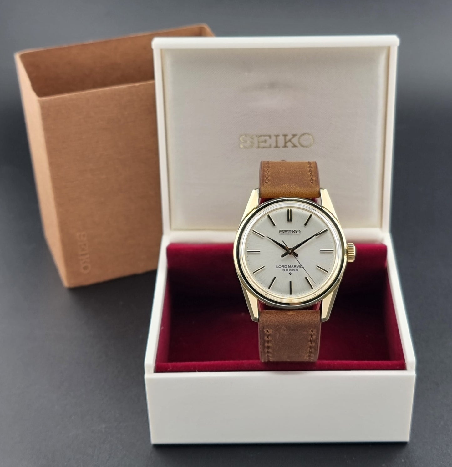 Vintage Seiko watch Lord Marvel 5740-8000 with brown leather strap and gold case on a dark background box view