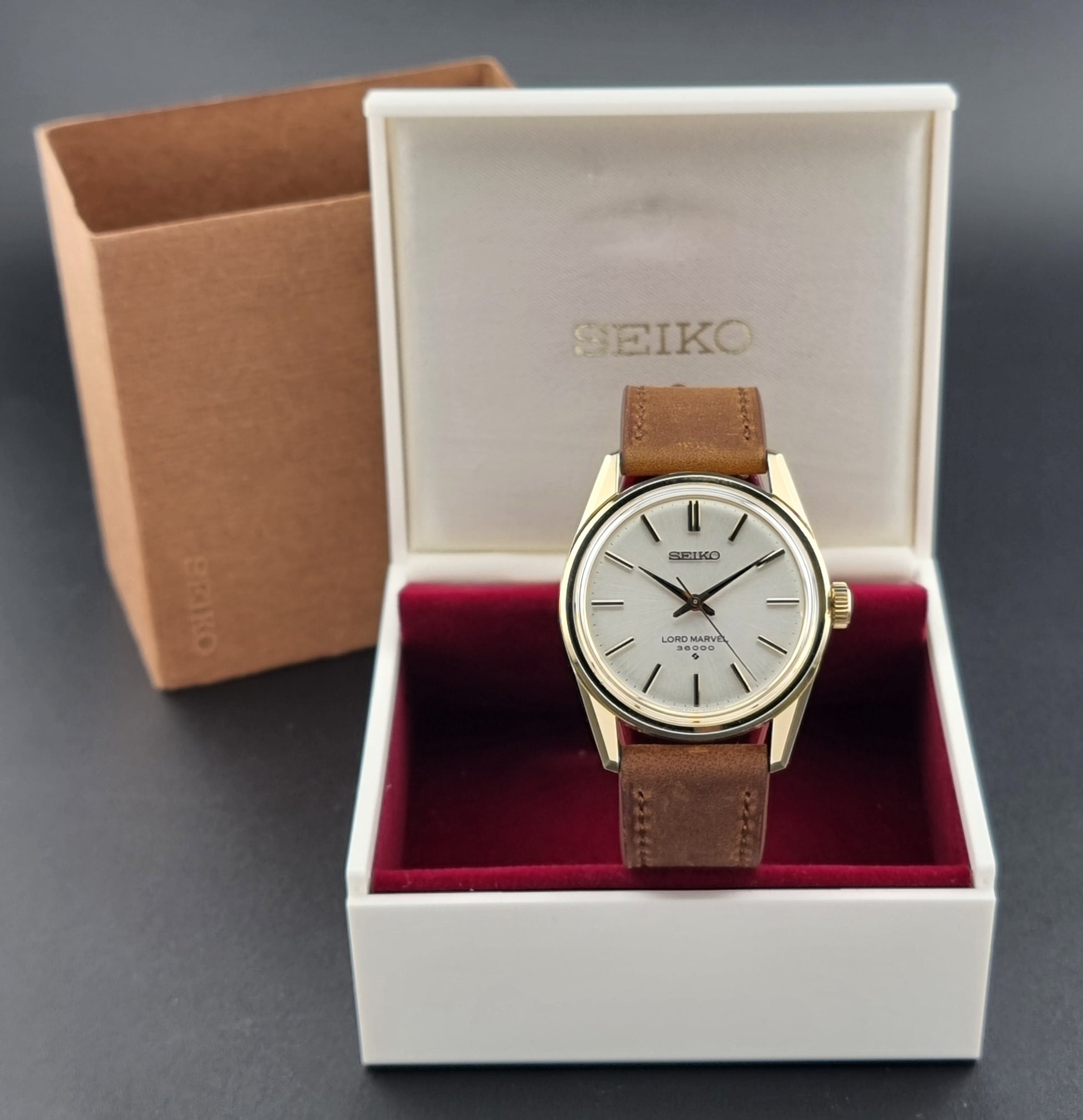Vintage Seiko watch Lord Marvel 5740-8000 with brown leather strap and gold case on a dark background box view