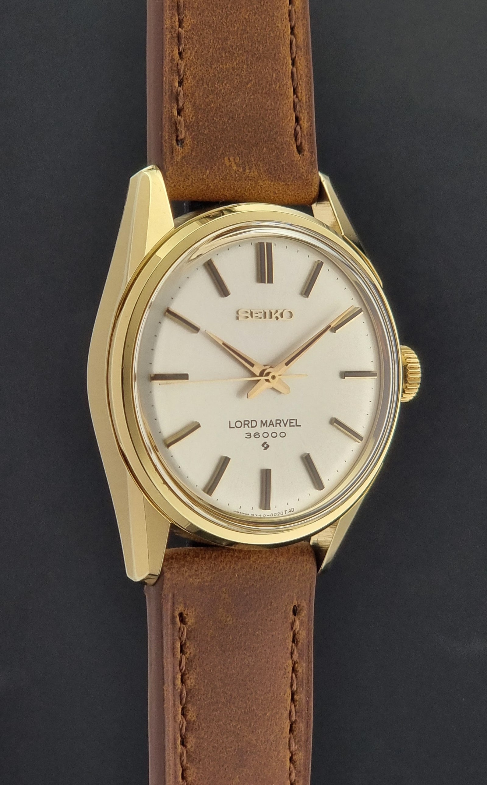 Vintage Seiko watch Lord Marvel 5740-8000 with brown leather strap and gold case on a dark background side profile view
