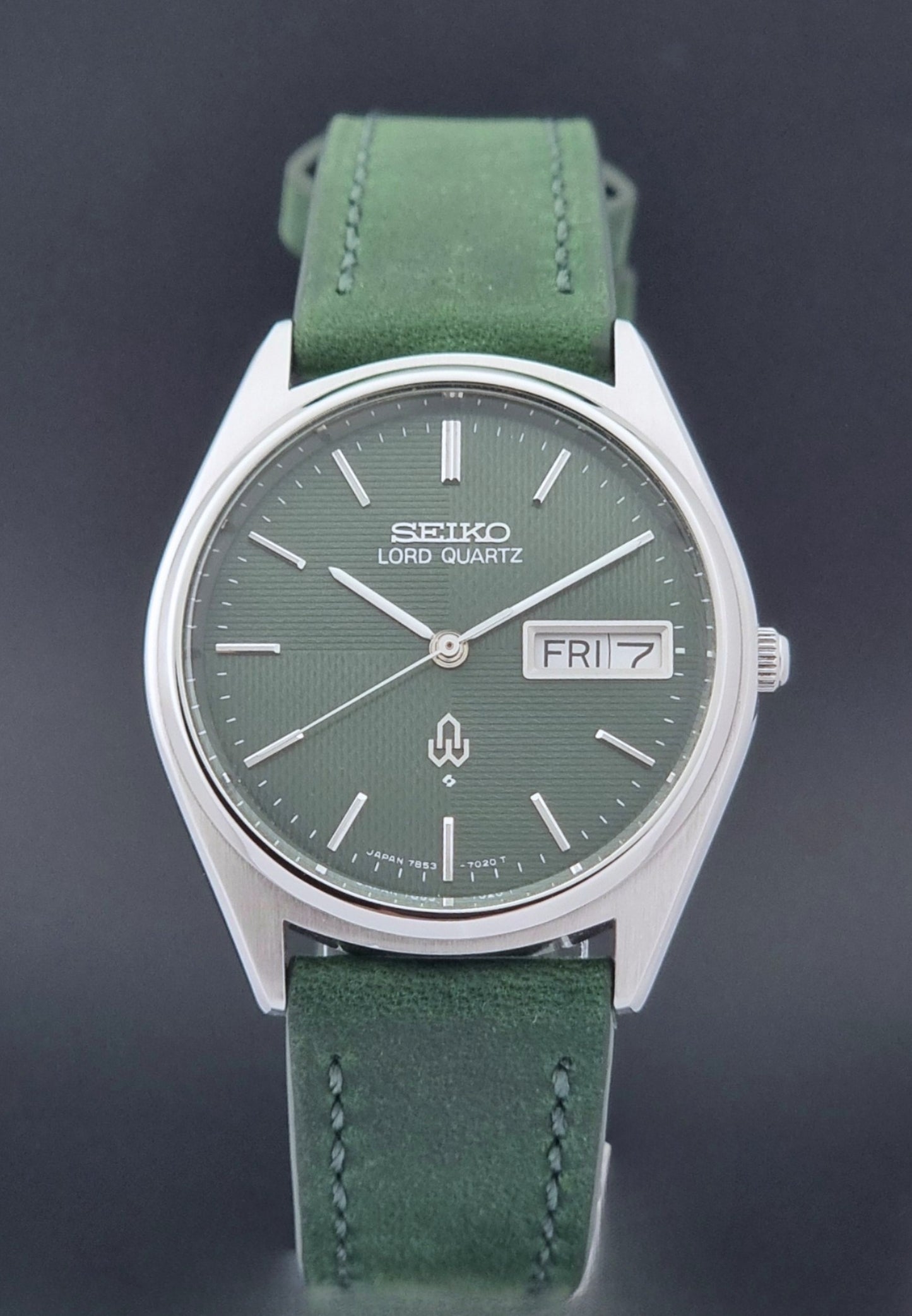 Vintage Seiko Lord Quartz watch 7853-7020 with green strap and silver case on a dark gray background close dial view