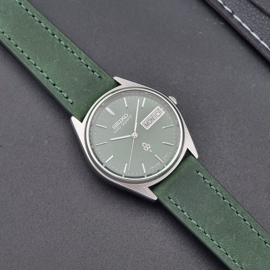 Vintage Seiko Lord Quartz watch 7853-7020 with green strap and silver case on a dark gray background dial