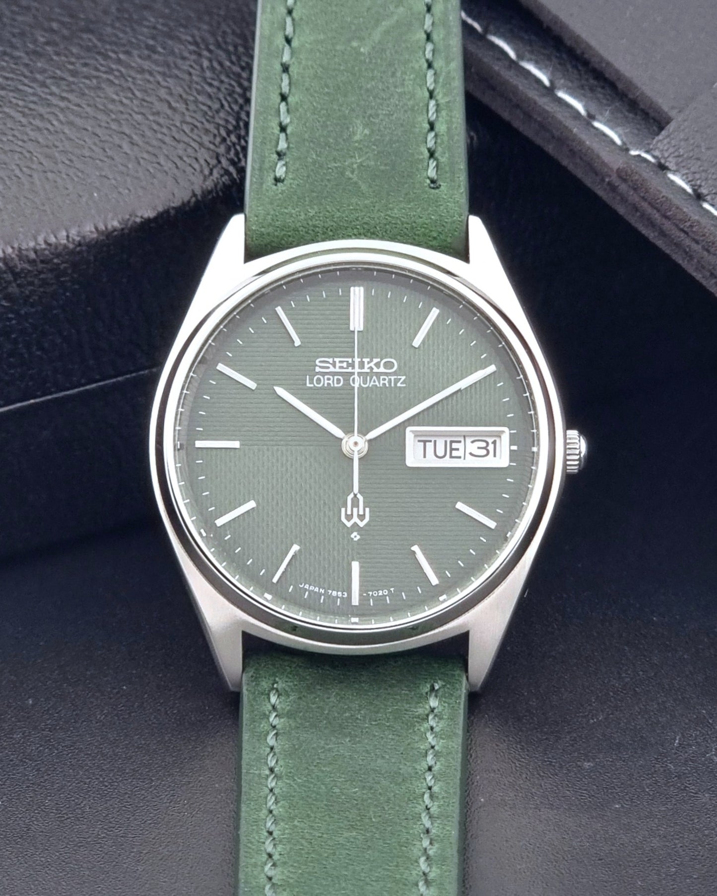 Vintage Seiko Lord Quartz watch 7853-7020 with green strap and silver case on a dark gray background dial view