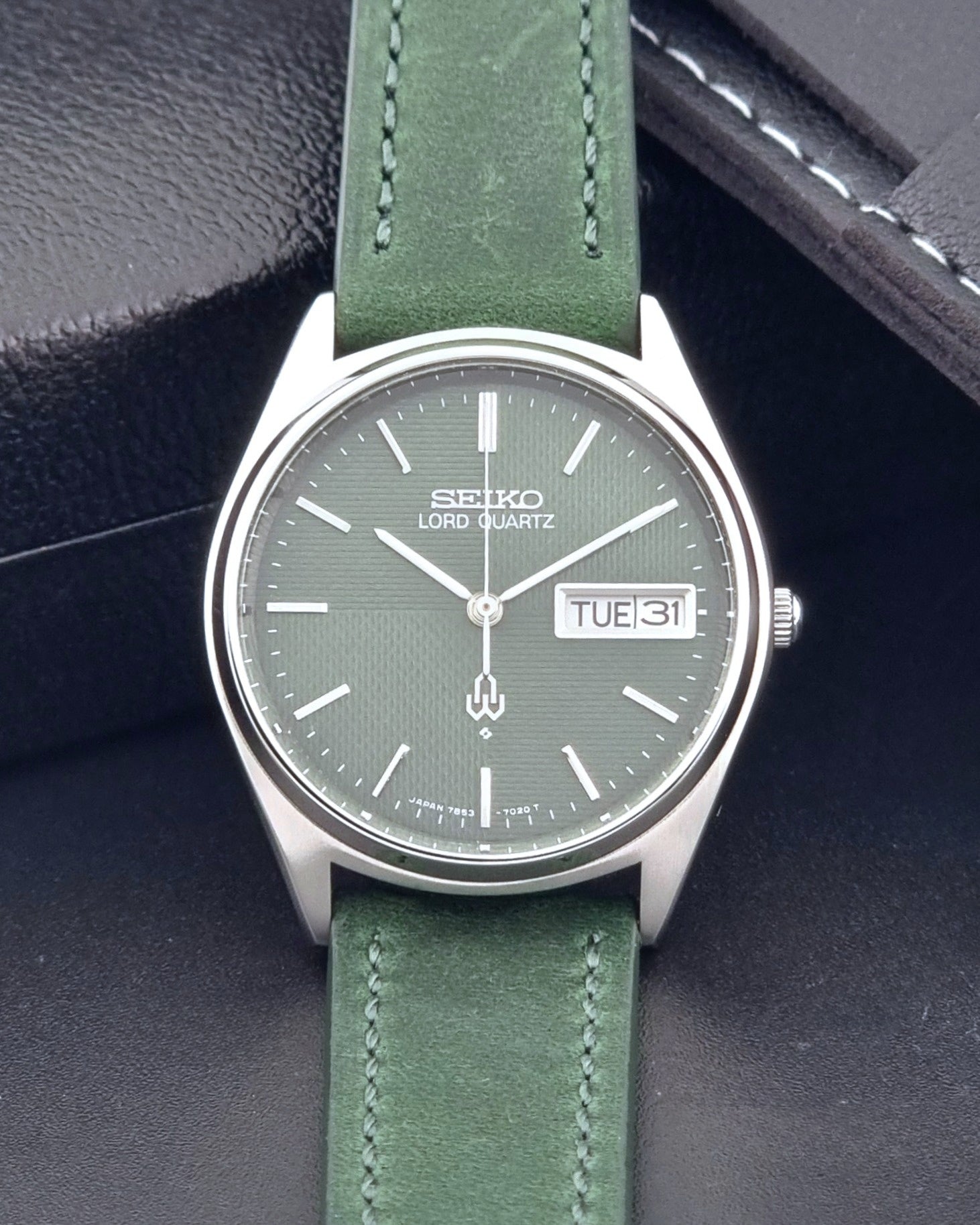 Vintage Seiko Lord Quartz watch 7853-7020 with green strap and silver case on a dark gray background dial view