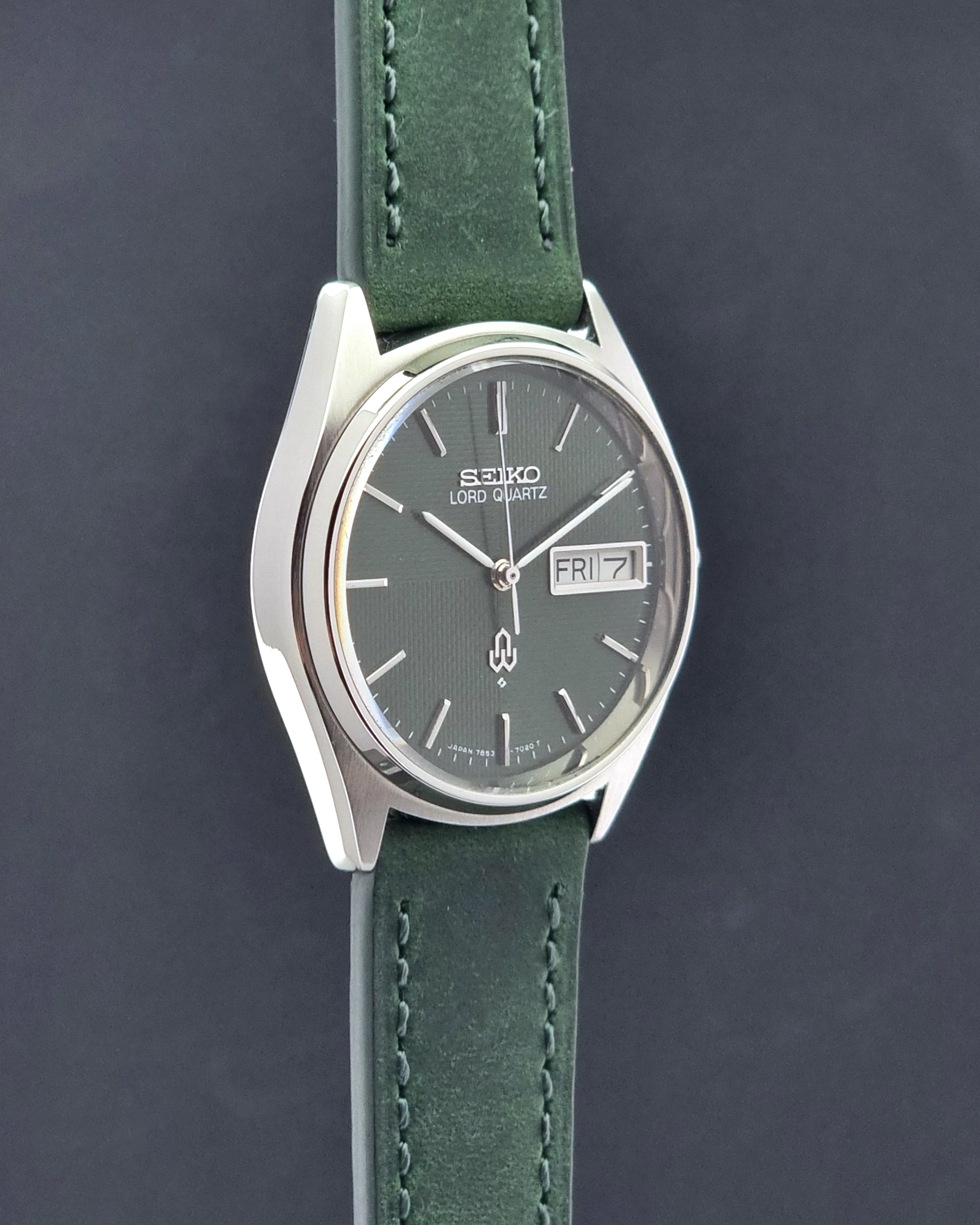 Vintage Seiko Lord Quartz watch 7853-7020 with green strap and silver case on a dark gray background side profile view