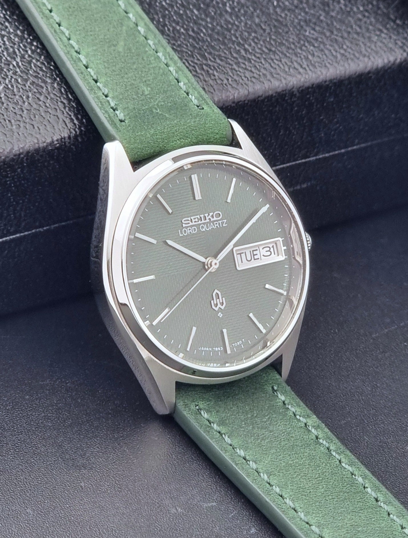 Vintage Seiko Lord Quartz watch 7853-7020 with green strap and silver case on a dark gray background side view