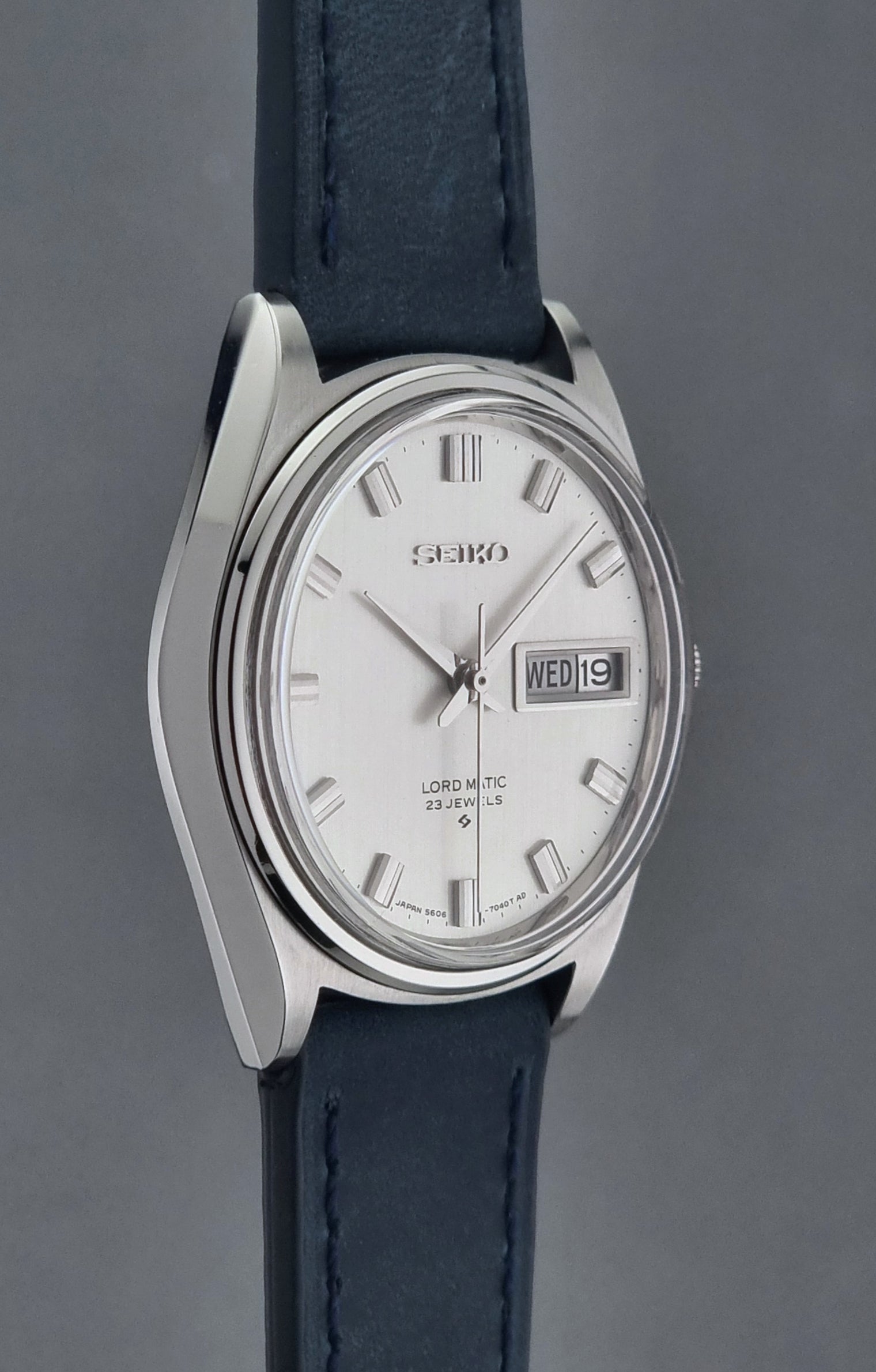 Seiko watch with a silver case and blue leather strap on a gray background