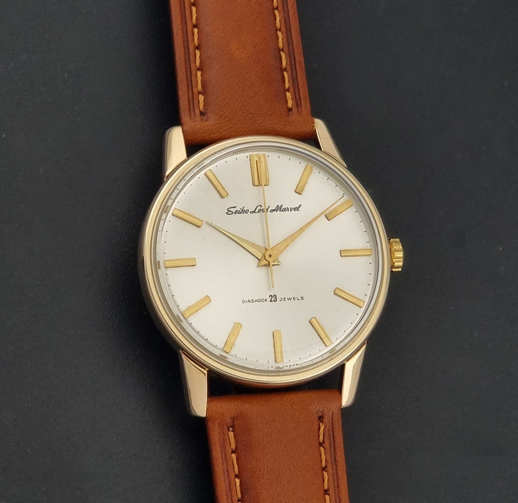 Vintage Seiko Lordmarvel Wristwatch 5740-1990 with a gold filled case and brown leather strap on a dark background front view