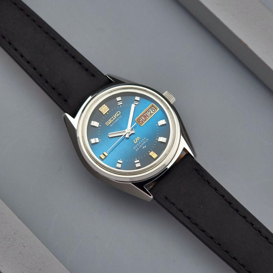 Vintage Seiko Lord Matic watch with blue dial and black strap on a gray surface