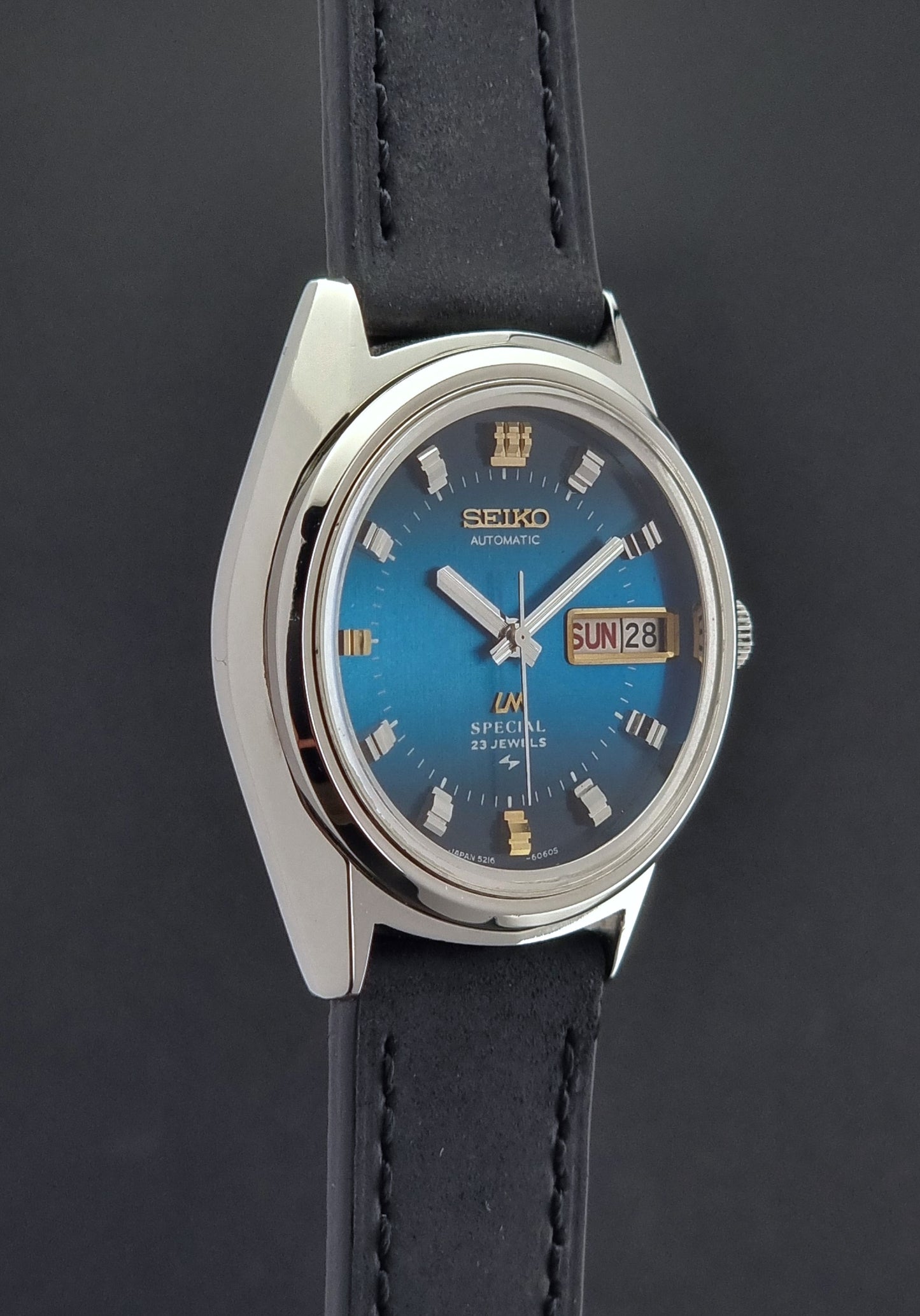 Vintage Seiko Lord Matic watch with blue face and black leather strap on a dark background