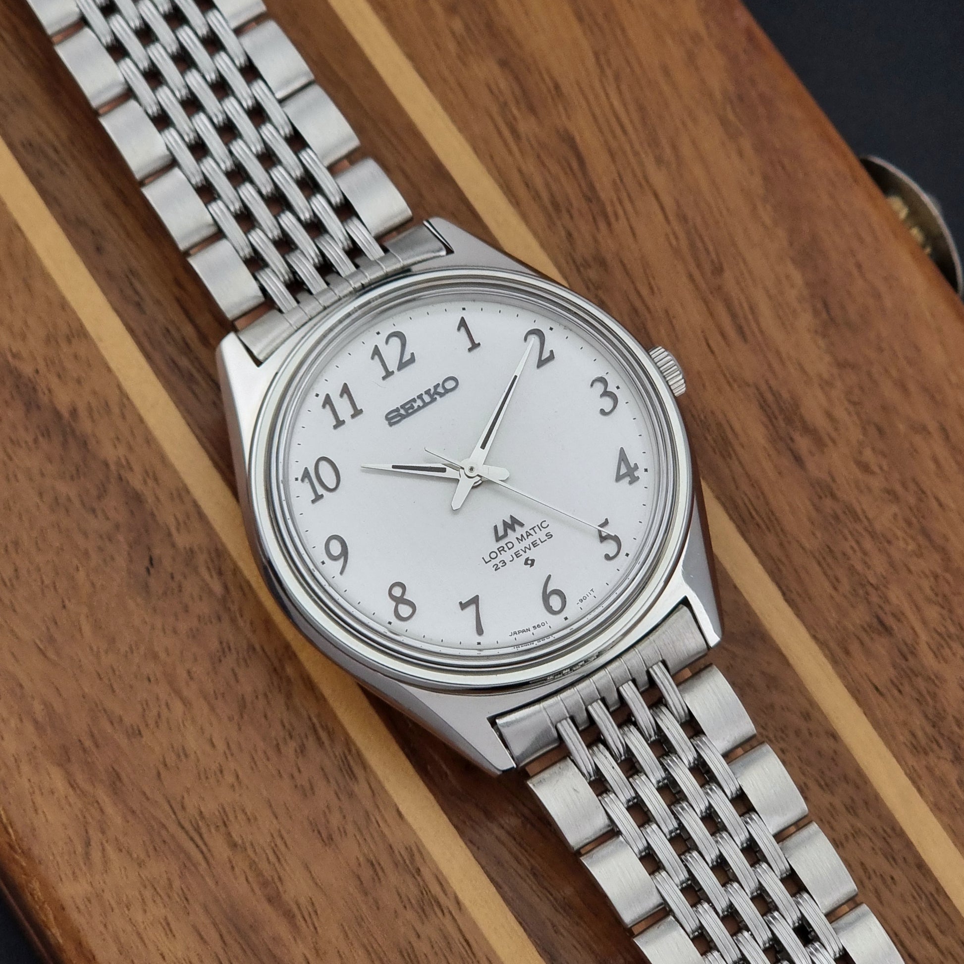 Silver Vintage Seiko watch LordMatic 5601-9000 with white face on a wooden surface