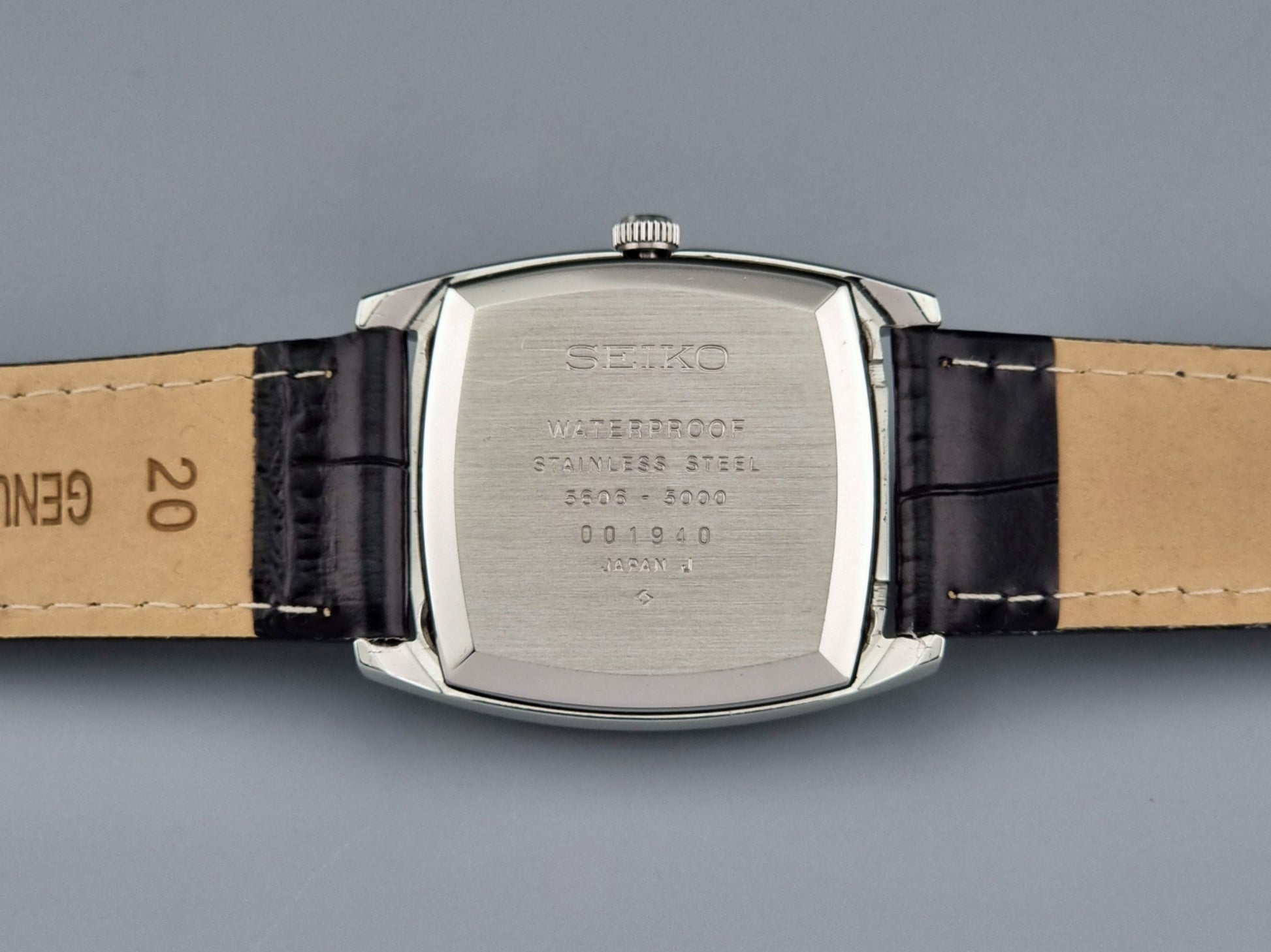 Seiko watch back with leather strap on a gray background