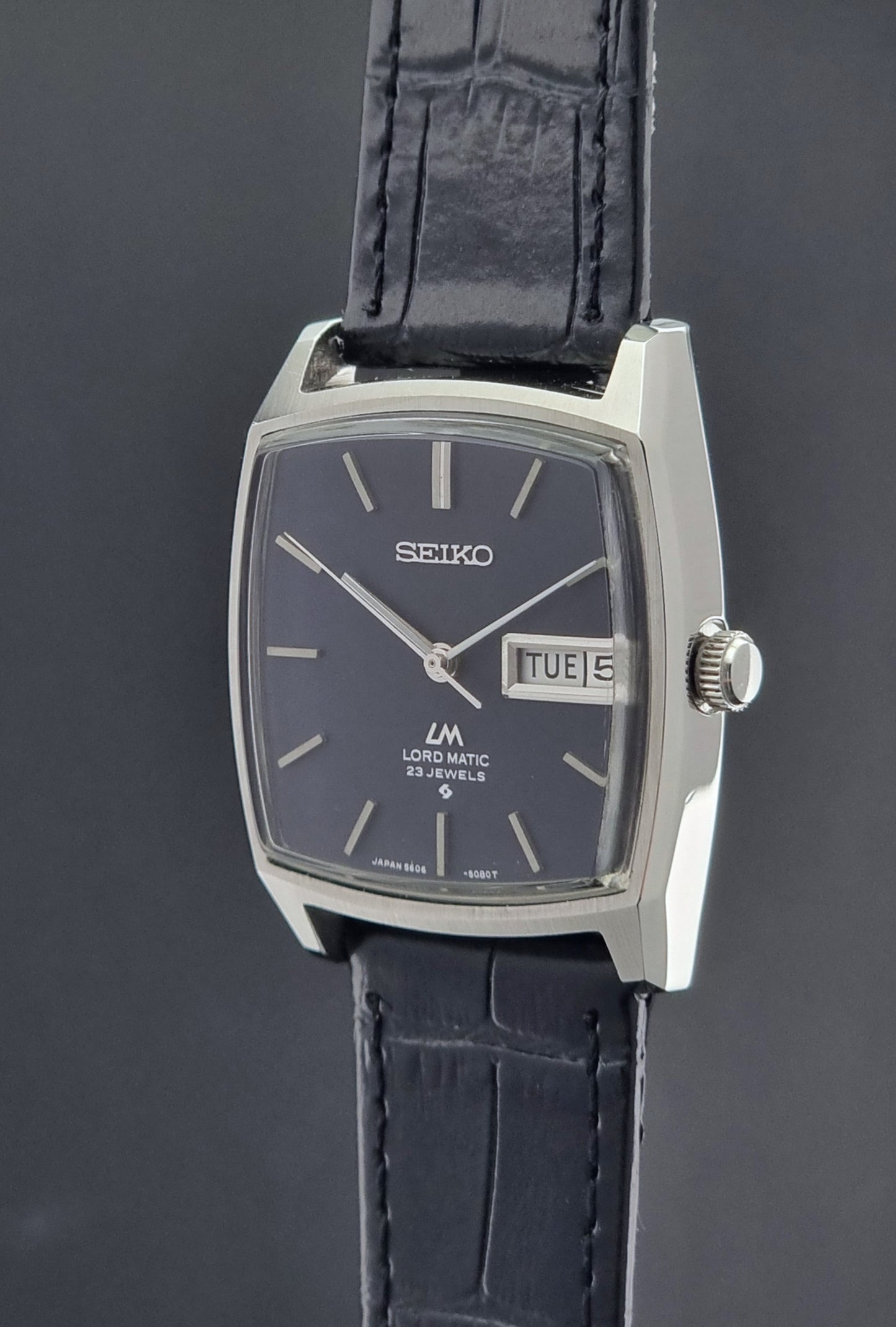 Seiko watch with black leather strap on a dark background