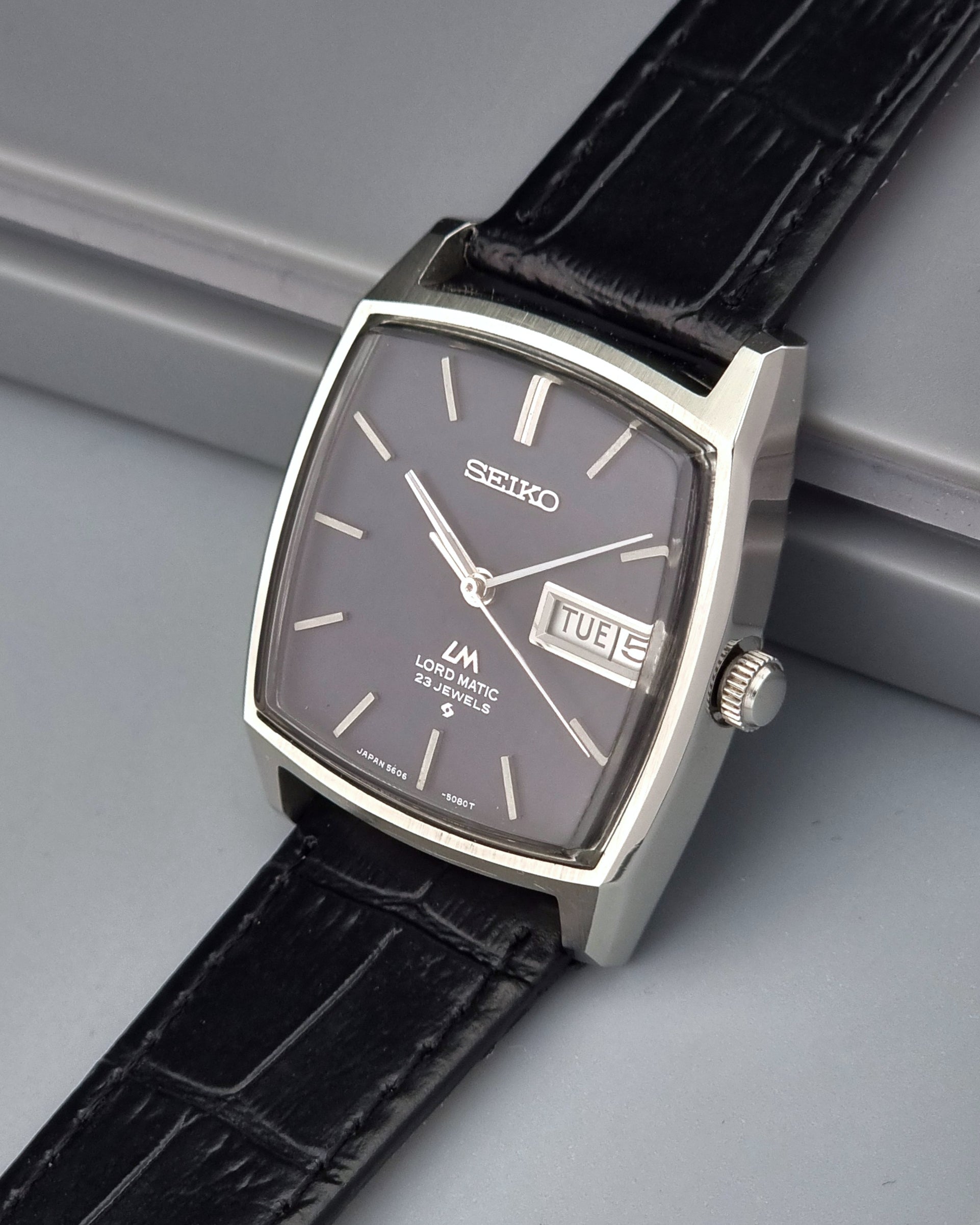 Vintage Seiko Lord Matic watch with black leather strap on a gray surface