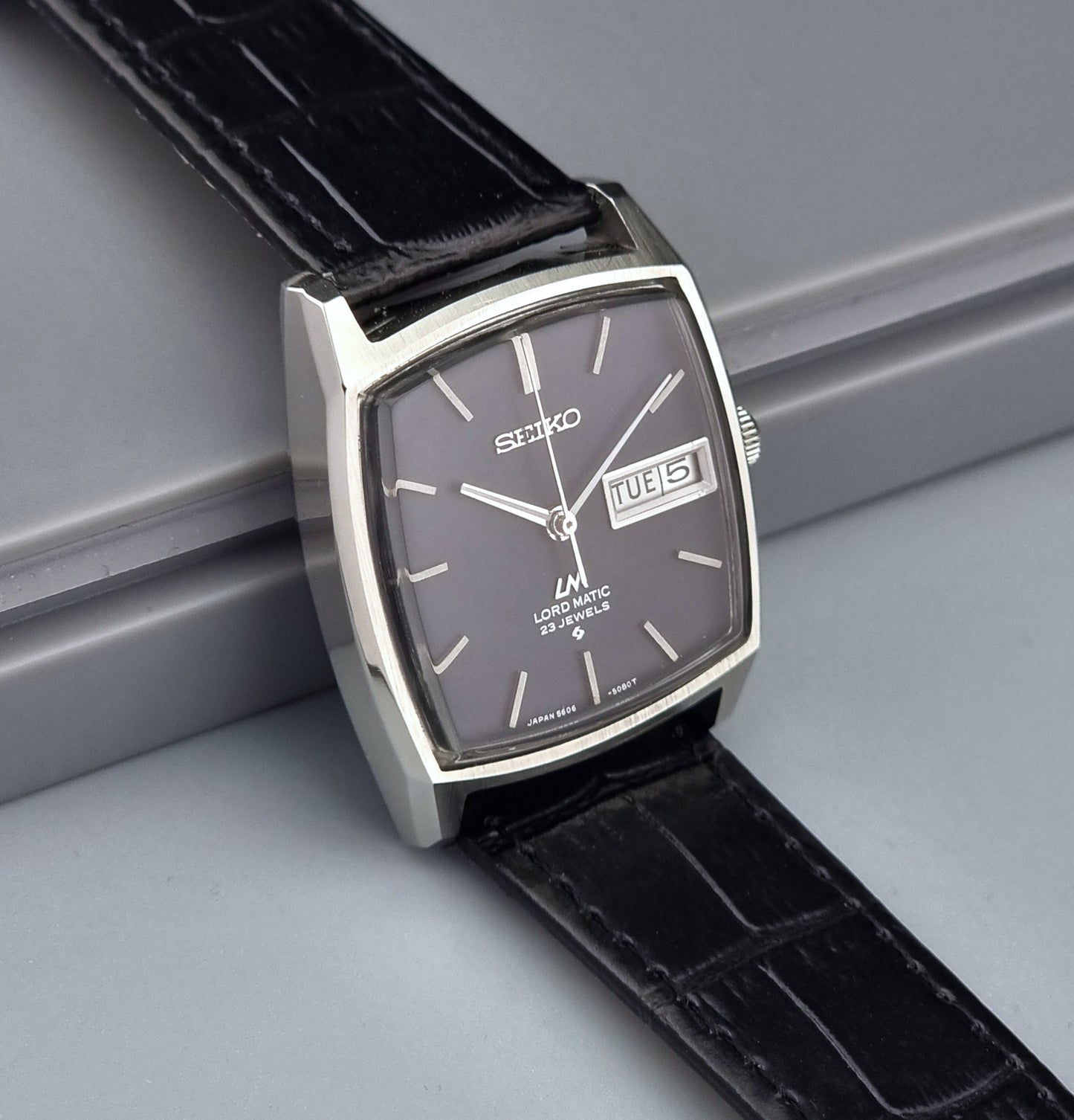 Vintage Seiko watch with black leather strap on a gray surface