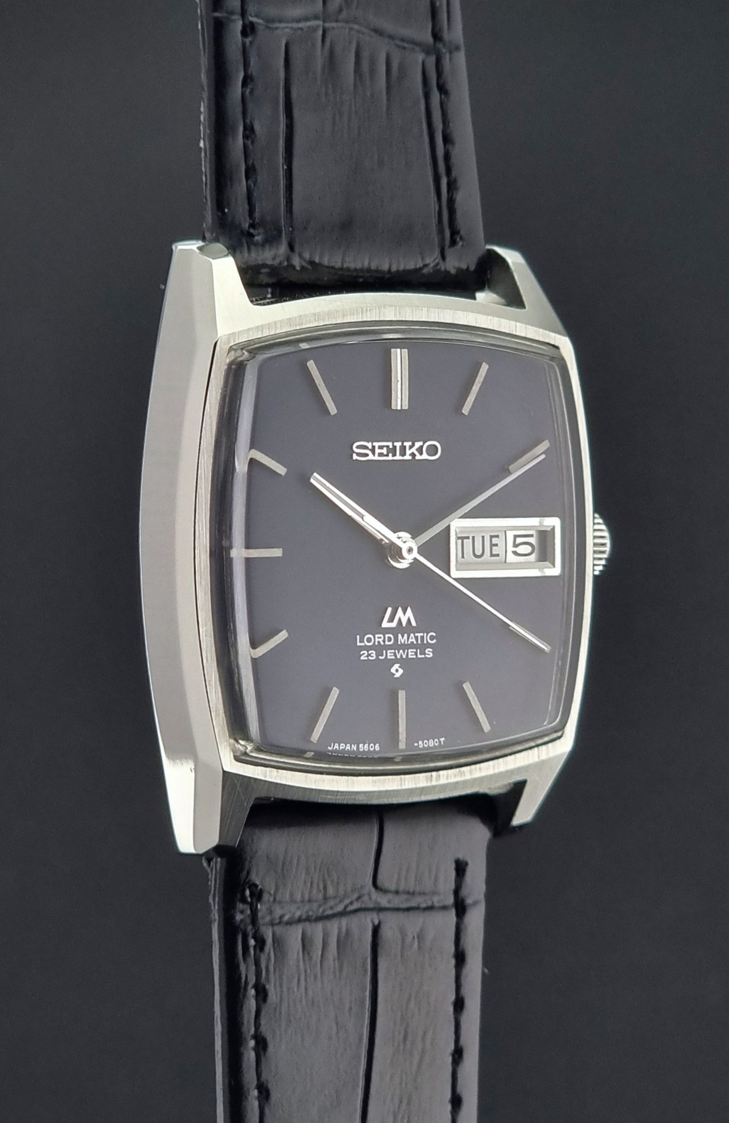 Seiko watch with black leather strap on a dark background
