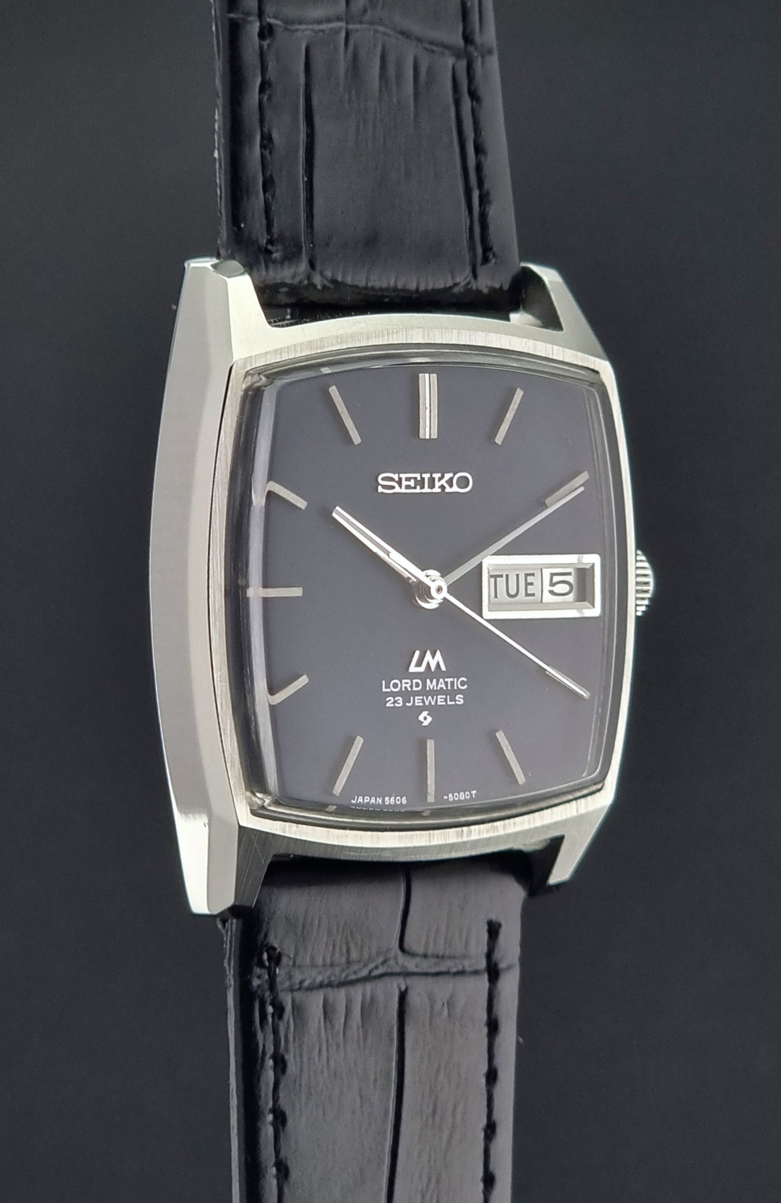 Seiko watch with black leather strap on a dark background