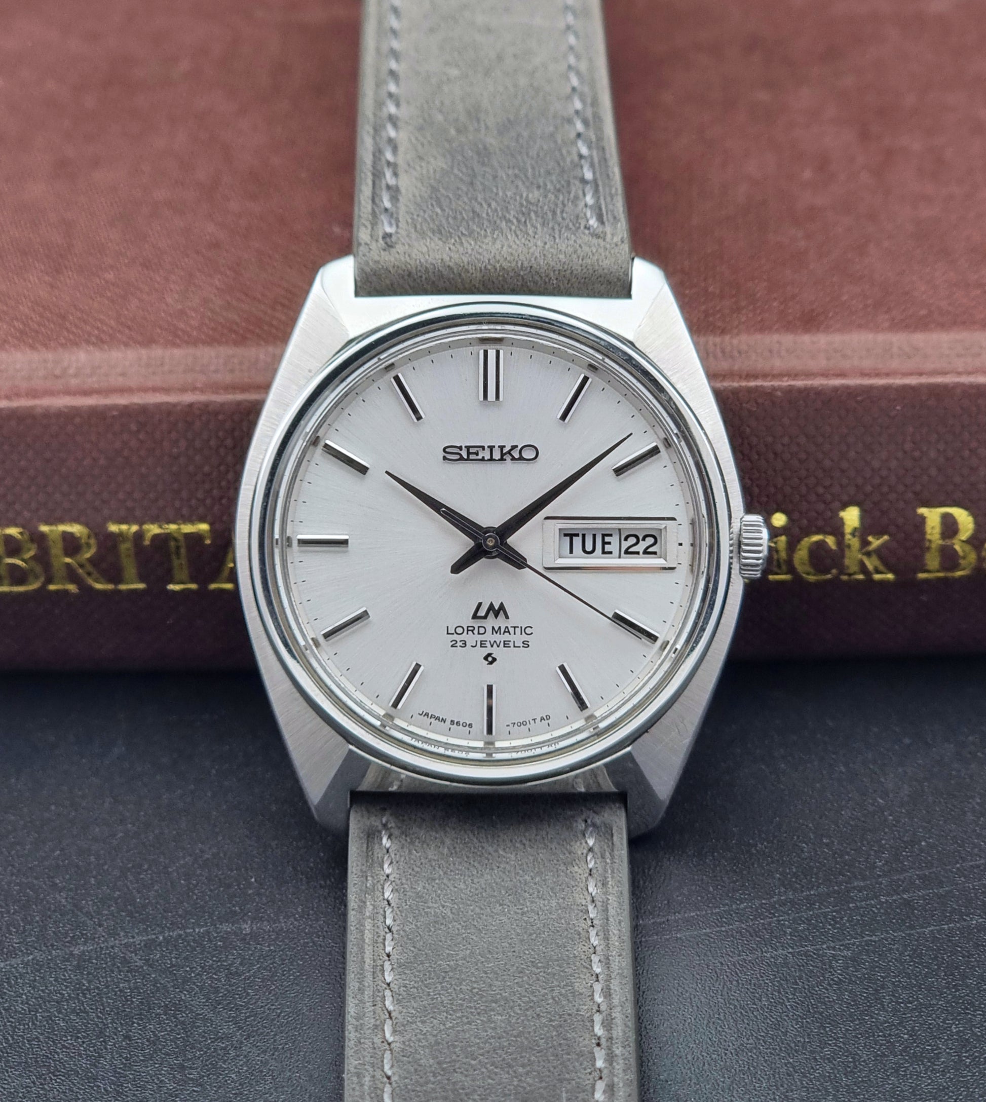 Vintage Seiko Wristwatch LordMatic 5606-7000 with gray strap on a dark surface front view