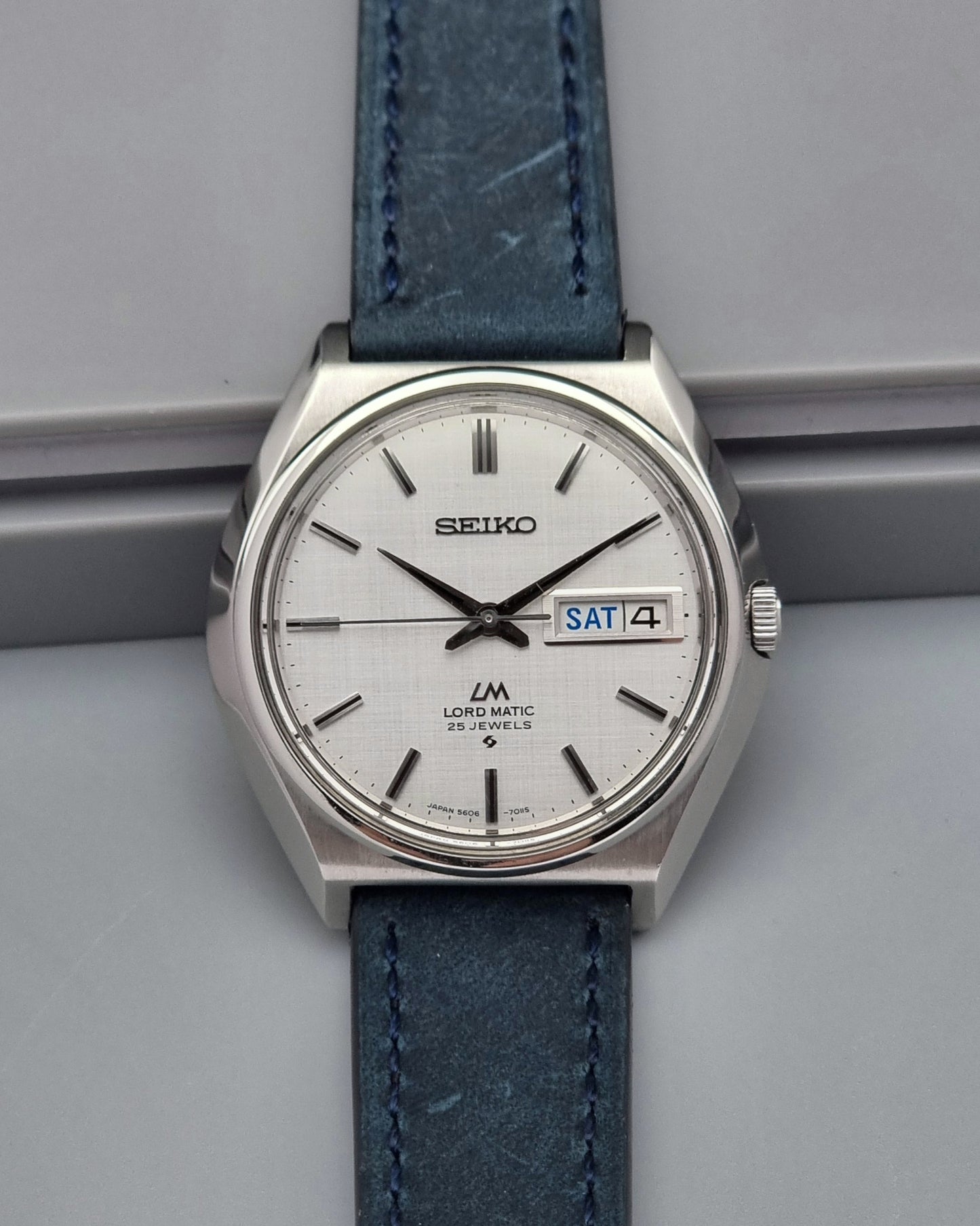 Vintage Seiko Wristwatch LordMatic 5606-7010 on a blue strap on a gray background