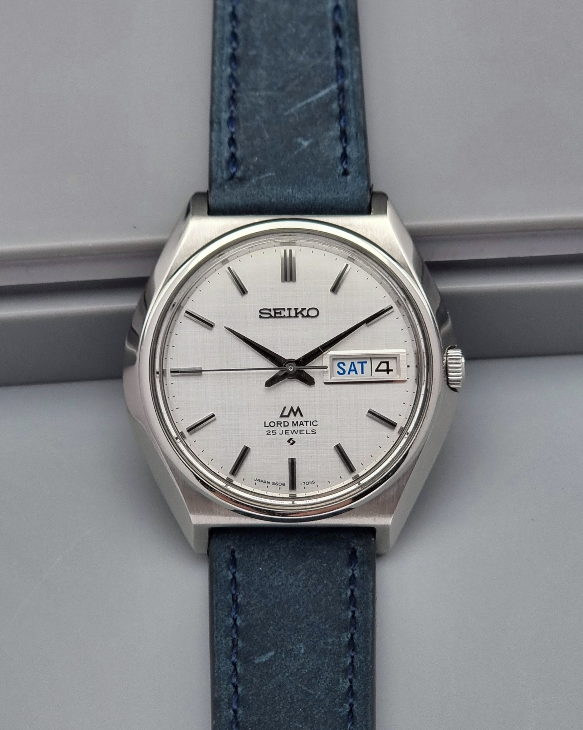 Vintage Seiko Wristwatch LordMatic 5606-7010 on a blue strap on a gray background