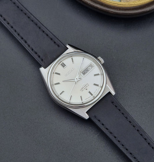 Vintage Seiko Wristwatch 5606-7020 LordMatic with a black strap on a dark gray background dial