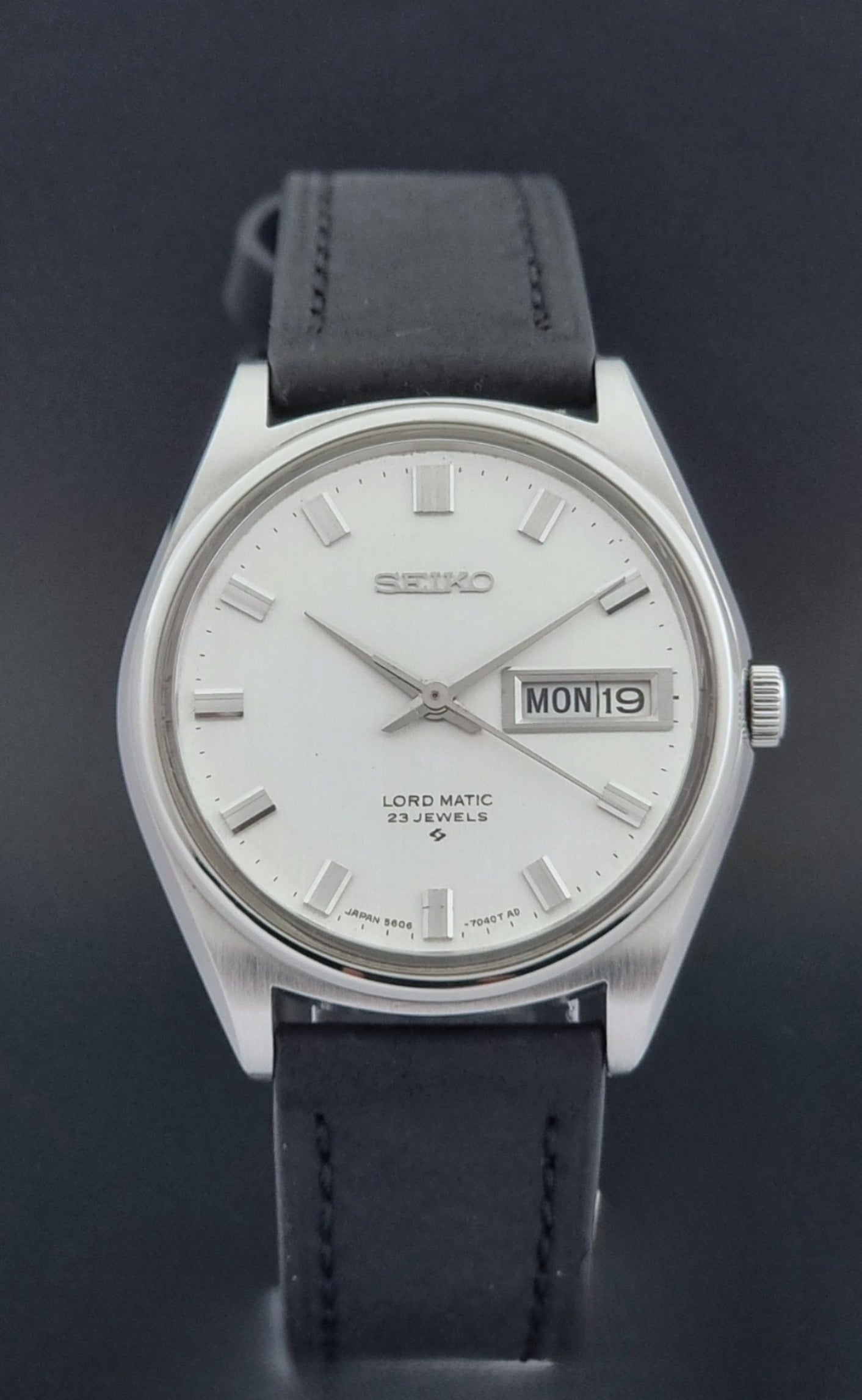 Vintage Seiko Wristwatch LordMatic 5606-7040 with black leather strap on a dark surface close dial view