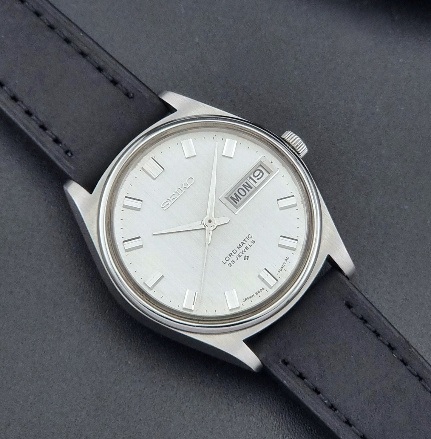 Vintage Seiko Wristwatch LordMatic 5606-7040 with black leather strap on a dark surface close up dial view