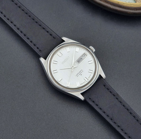 Vintage Seiko Wristwatch LordMatic 5606-7040 with black leather strap on a dark surface dial