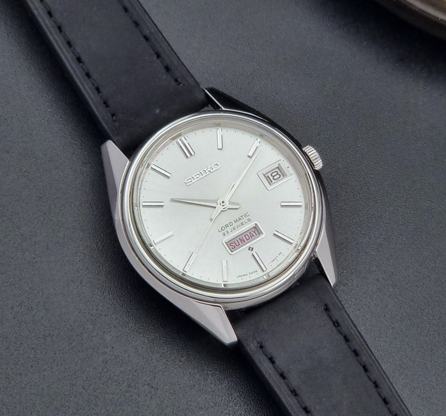Vintage Seiko Wristwatch 5606-7060 LordMatic Weekdater with black leather strap on a dark gray background close up dial view
