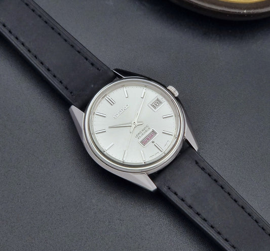 Vintage Seiko Wristwatch 5606-7060 LordMatic Weekdater with black leather strap on a dark gray background dial