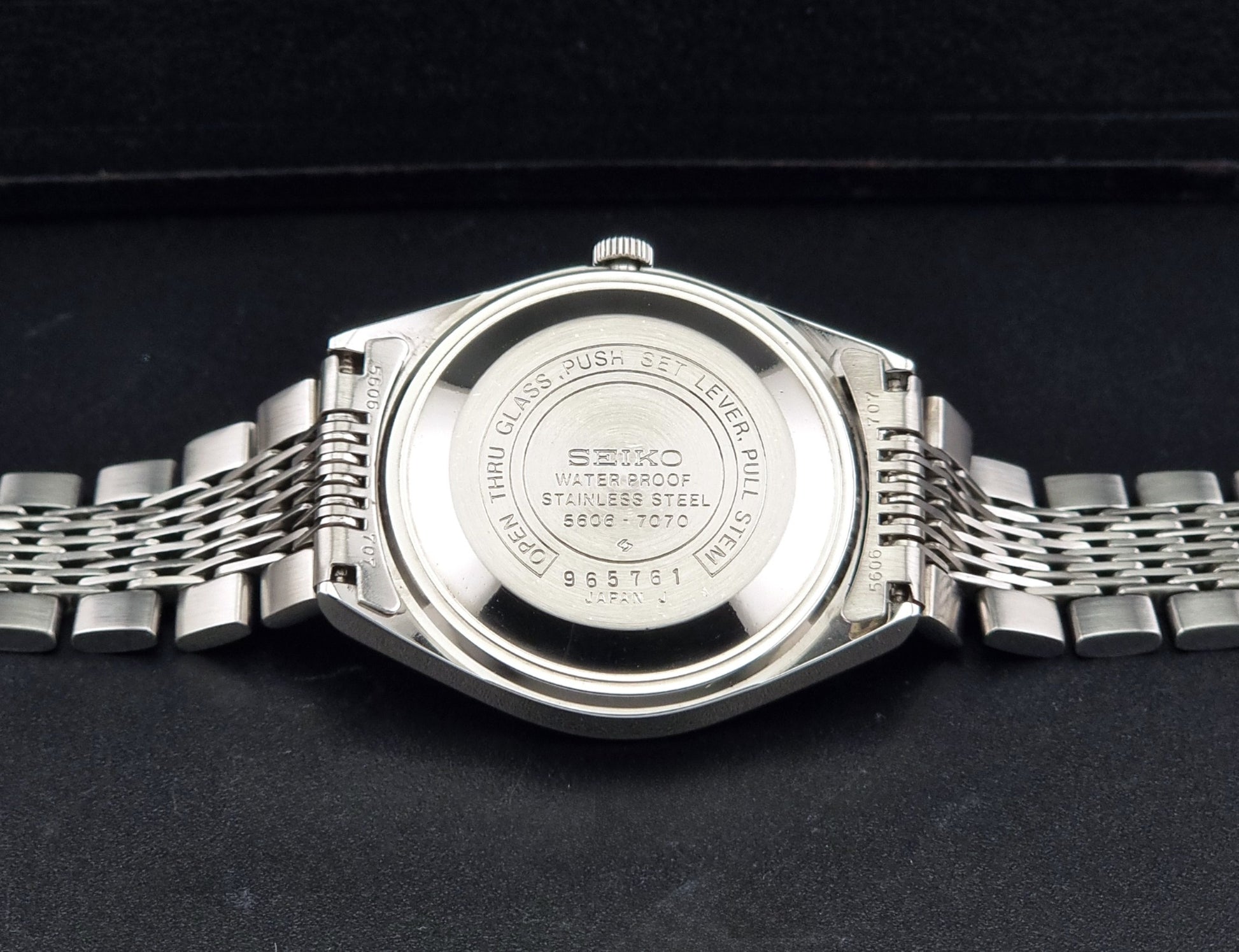 Vintage Seiko 5606-7070 watch LordMatic with a white face on a dark gray background case back view