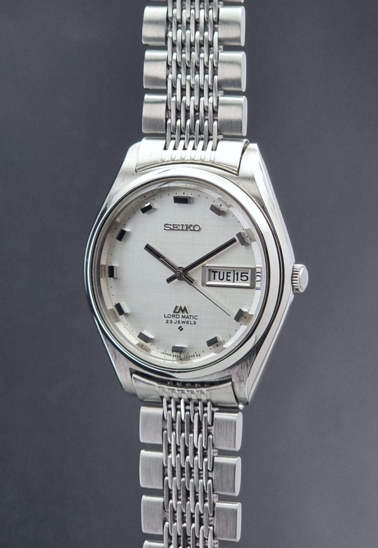Vintage Seiko 5606-7070 watch LordMatic with a white face on a dark gray background crown profile view
