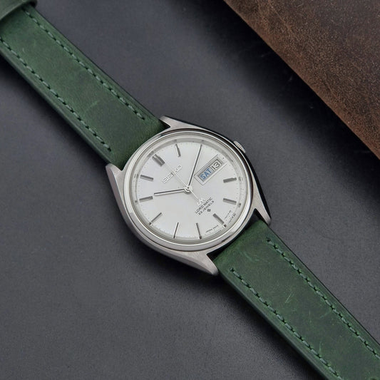 Vintage Seiko Wristwatch 5606-7070 LordMatic with green strap on a dark surface dial