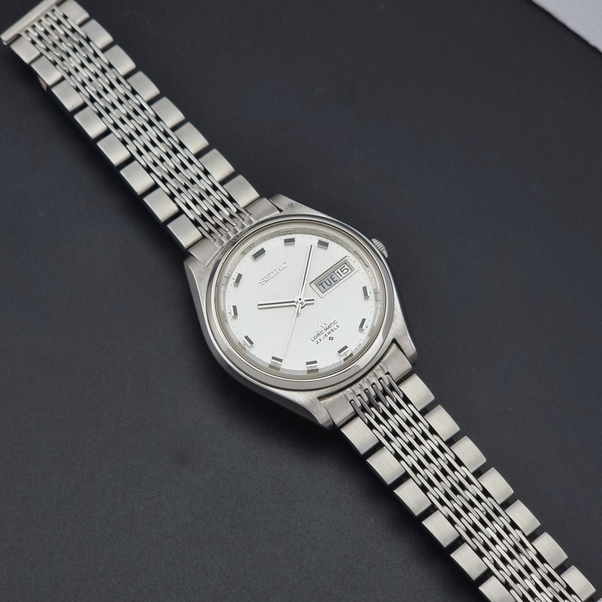 Vintage Seiko 5606-7070 watch LordMatic with a white face on a dark gray background dial