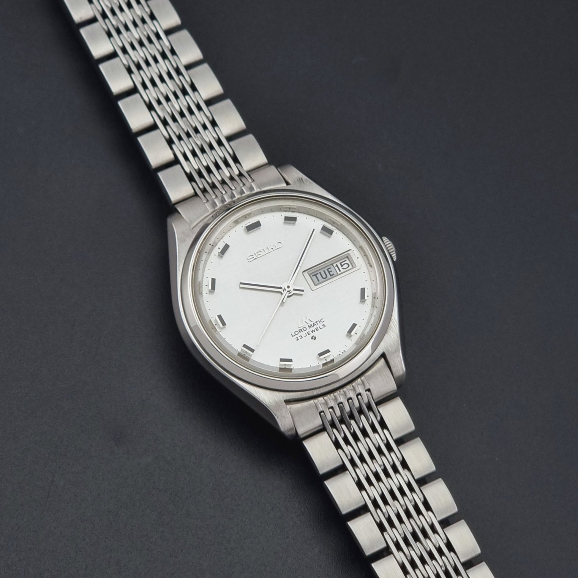 Vintage Seiko 5606-7070 watch LordMatic with a white face on a dark gray background close up dial view
