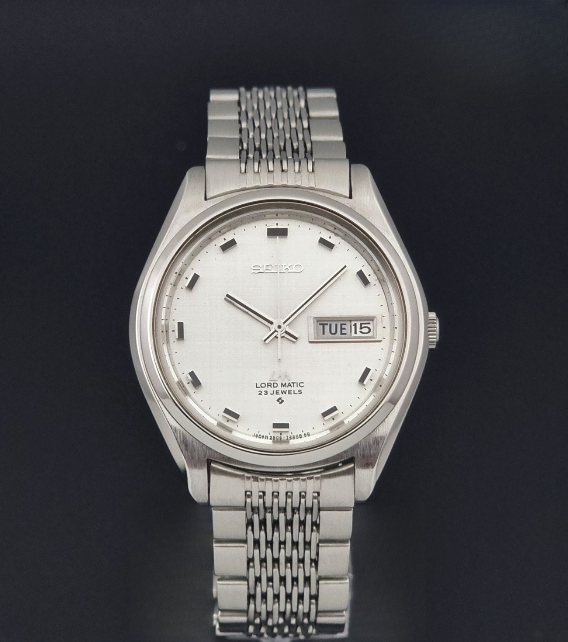 Vintage Seiko 5606-7070 watch LordMatic with a white face on a dark gray background close dial view