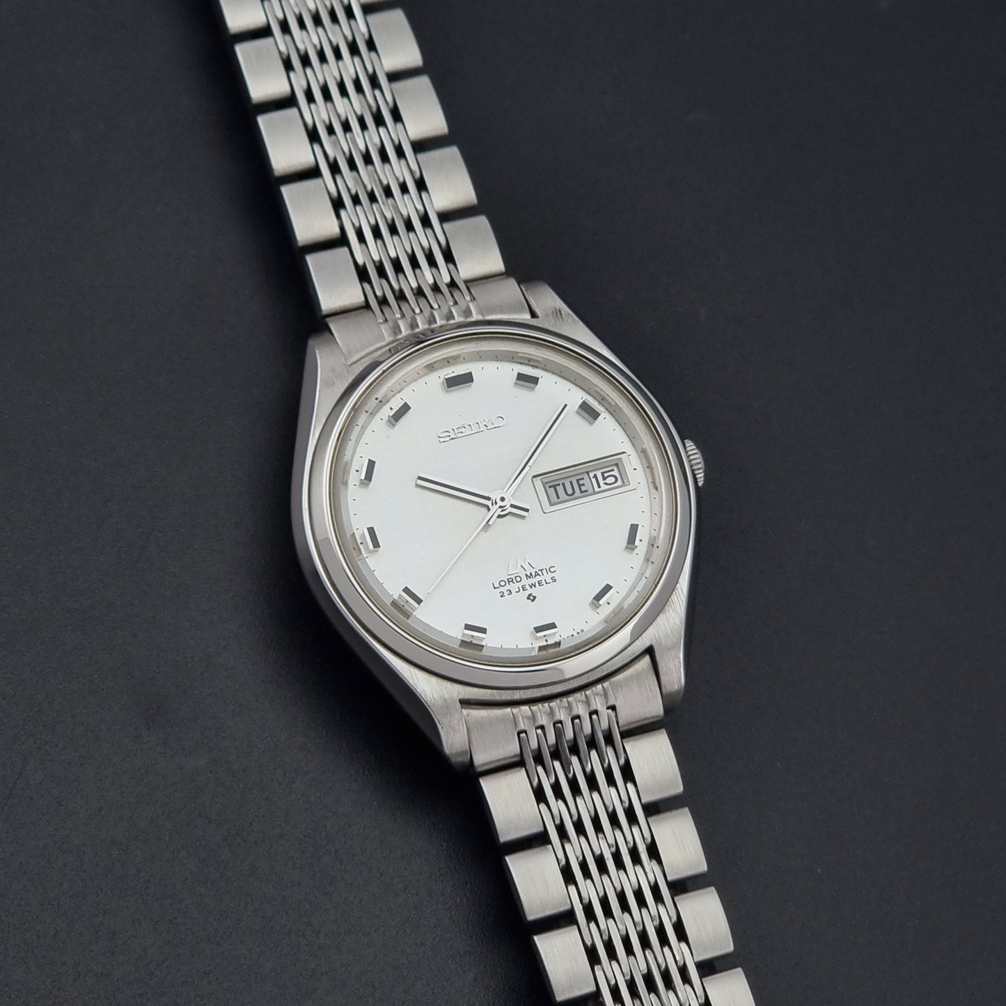 Vintage Seiko 5606-7070 watch LordMatic with a white face on a dark gray background front view
