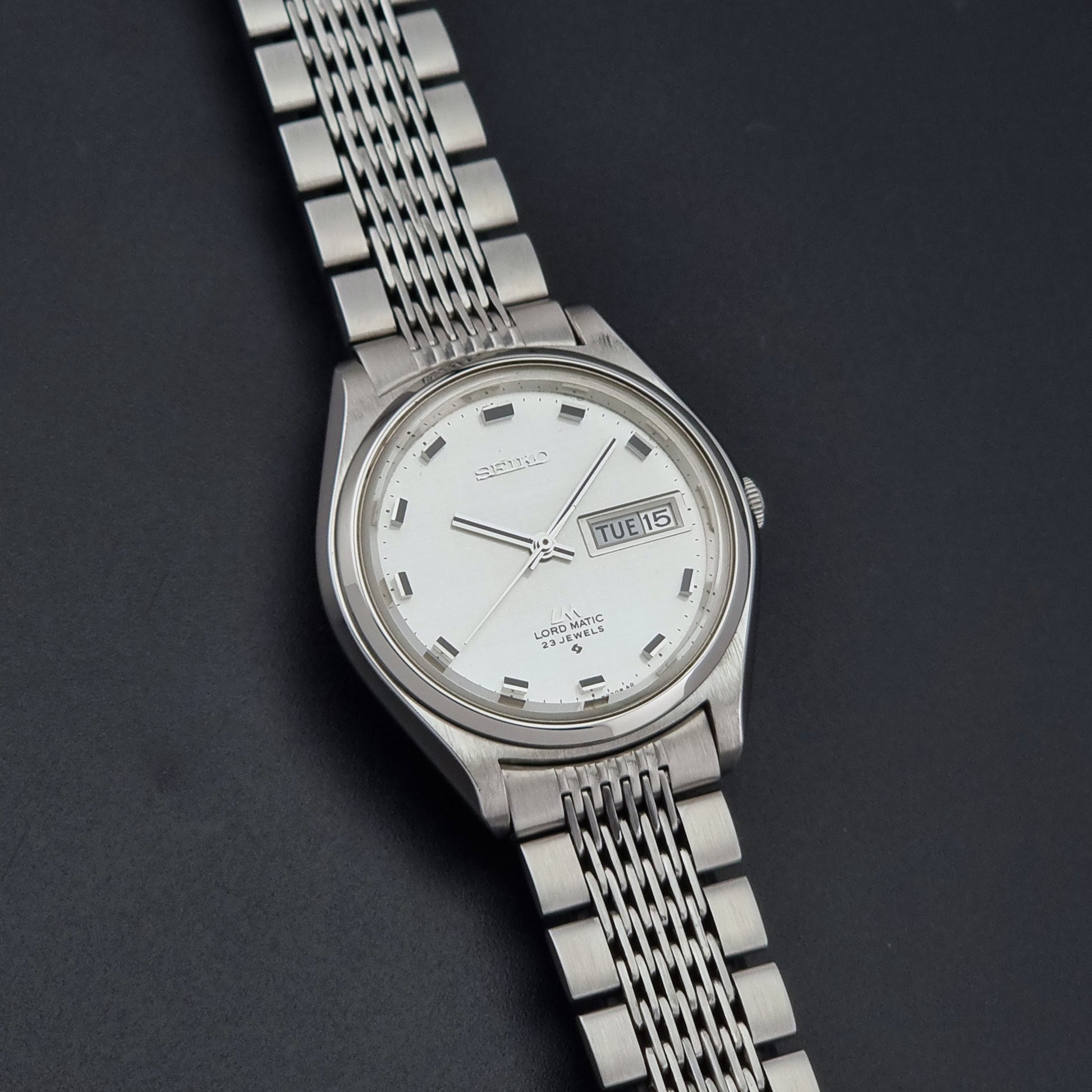 Vintage Seiko 5606-7070 watch LordMatic with a white face on a dark gray background front view