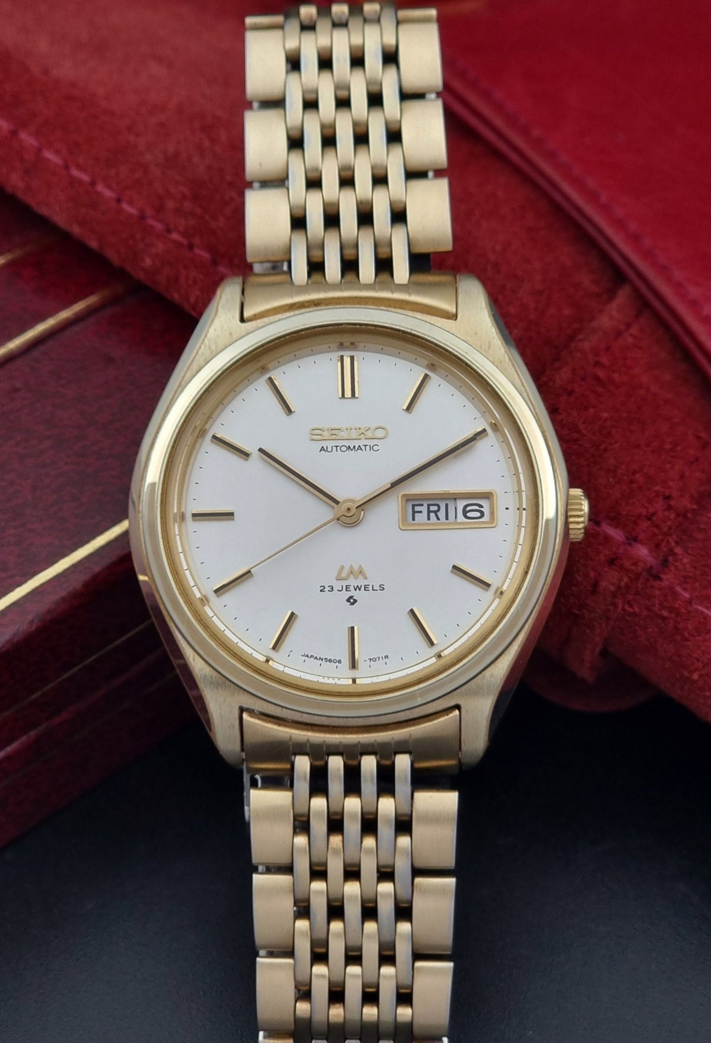 Vintage Seiko LordMatic 5606-7070 Gold wristwatch with a white face on a dark surface dial view