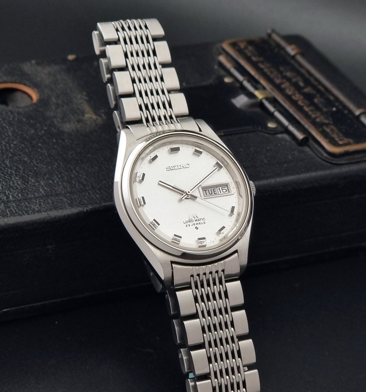 Vintage Seiko 5606-7070 watch LordMatic with a white face on a dark gray background side view