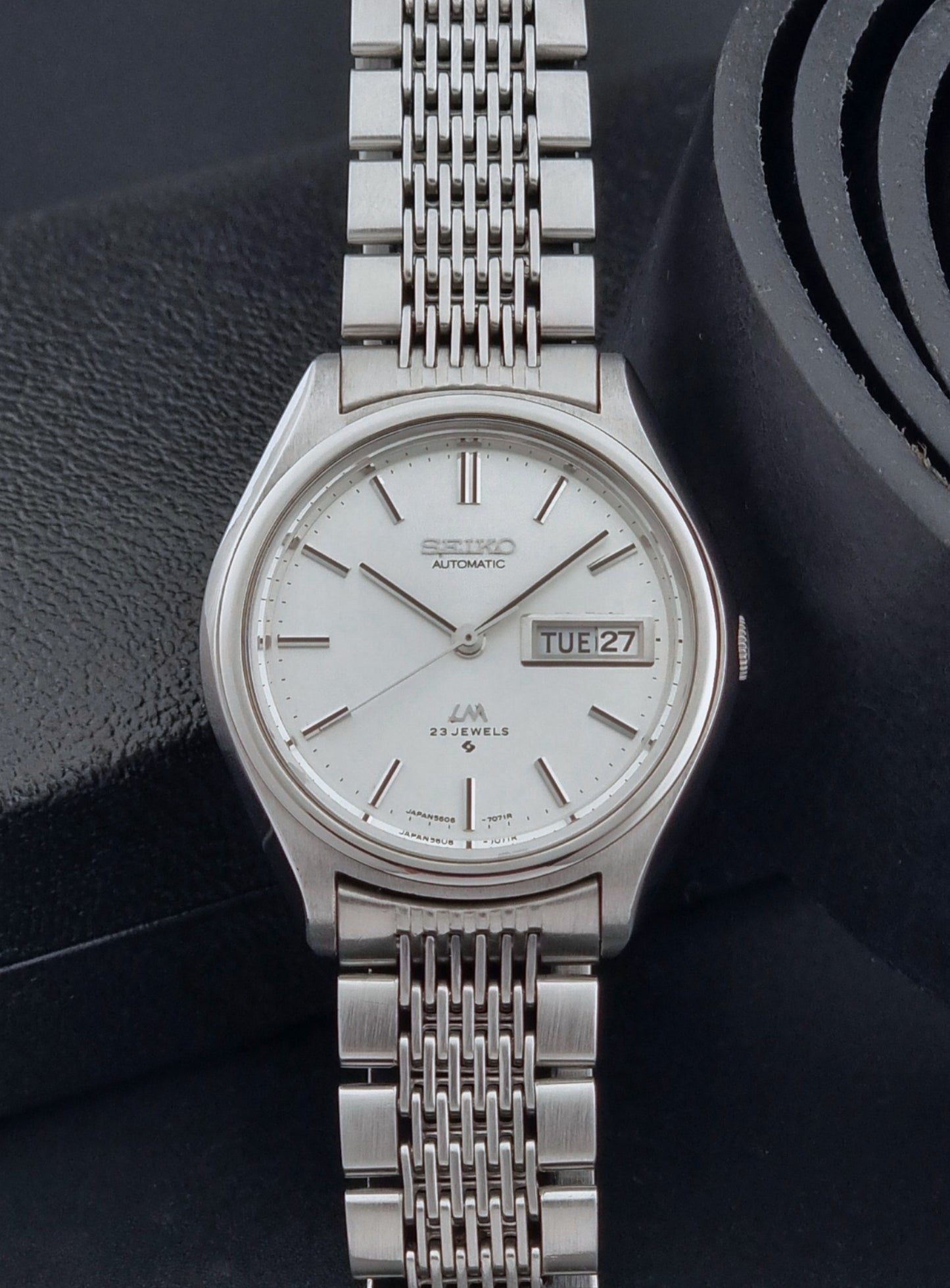 Vintage Seiko Wristwatch 5606-7071  with a metallic band on a dark background close up dial view