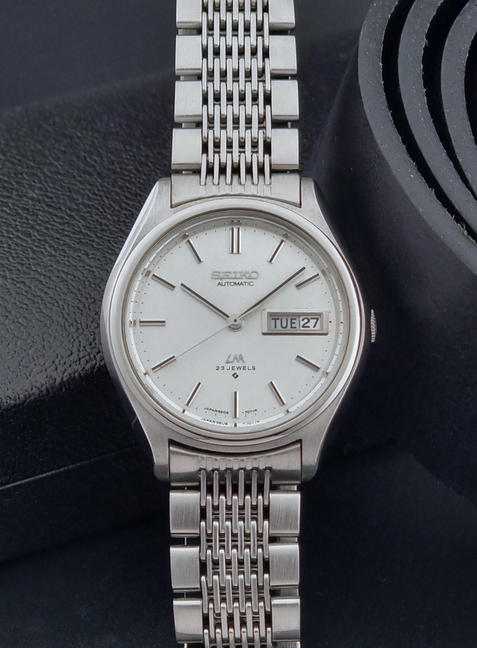 Vintage Seiko Wristwatch 5606-7071  with a metallic band on a dark background close up dial view